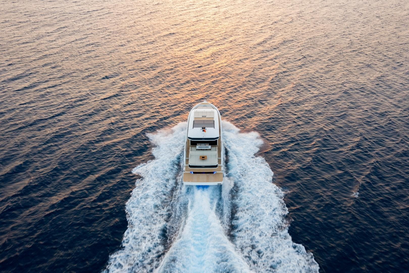 Aerial view of 2026 De Antonio Yachts D60 cruising on open water at sunset.