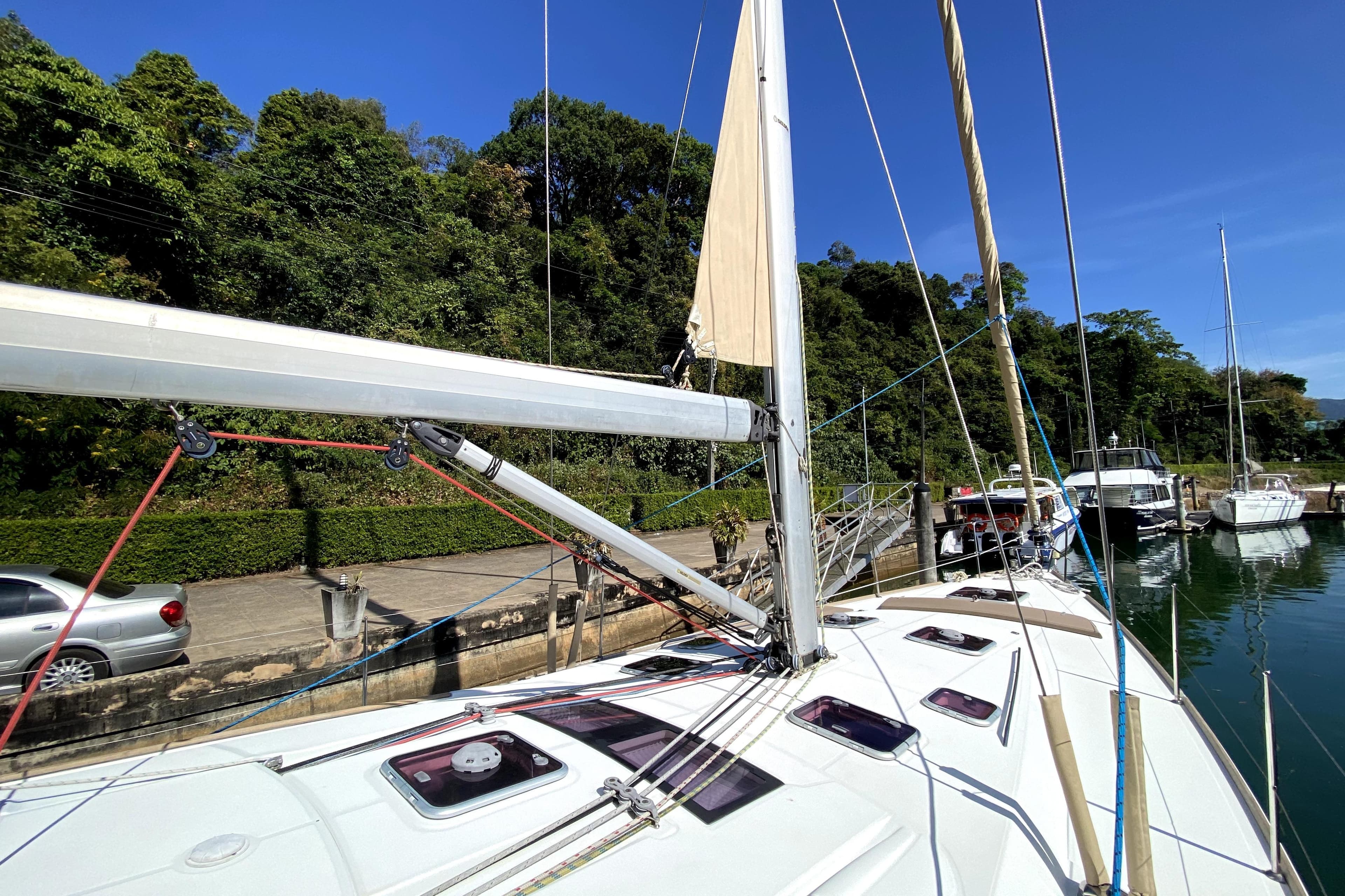 2013 Beneteau Oceanis 54 sailboat docked, surrounded by lush greenery and clear blue sky.