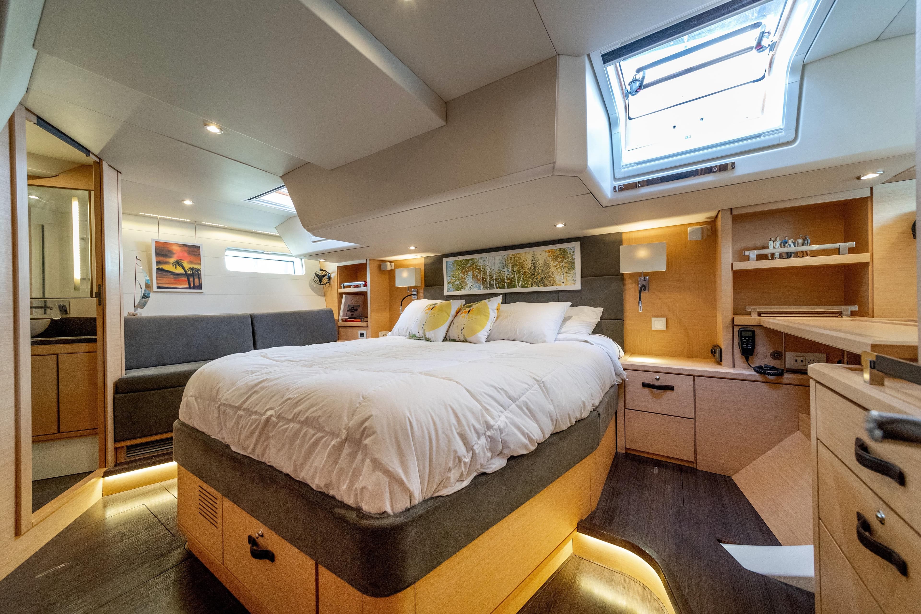 Luxurious 2016 Jeanneau 64 yacht bedroom with skylight, modern decor, and cozy ambiance.