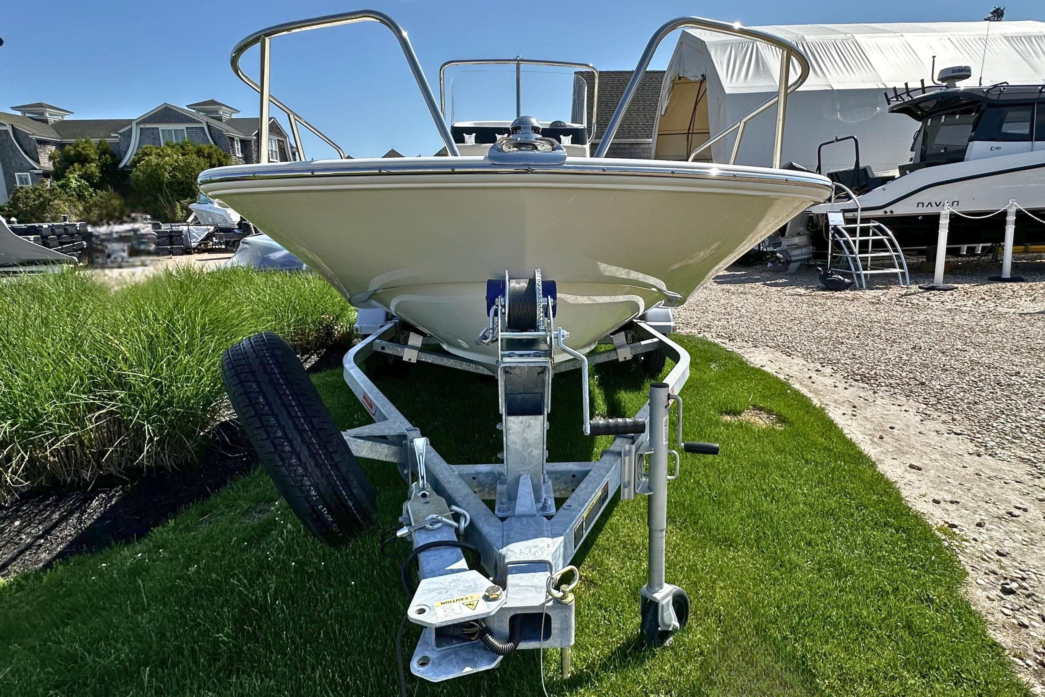 2026 Boston Whaler 150 Montauk boat on trailer, parked on grass.