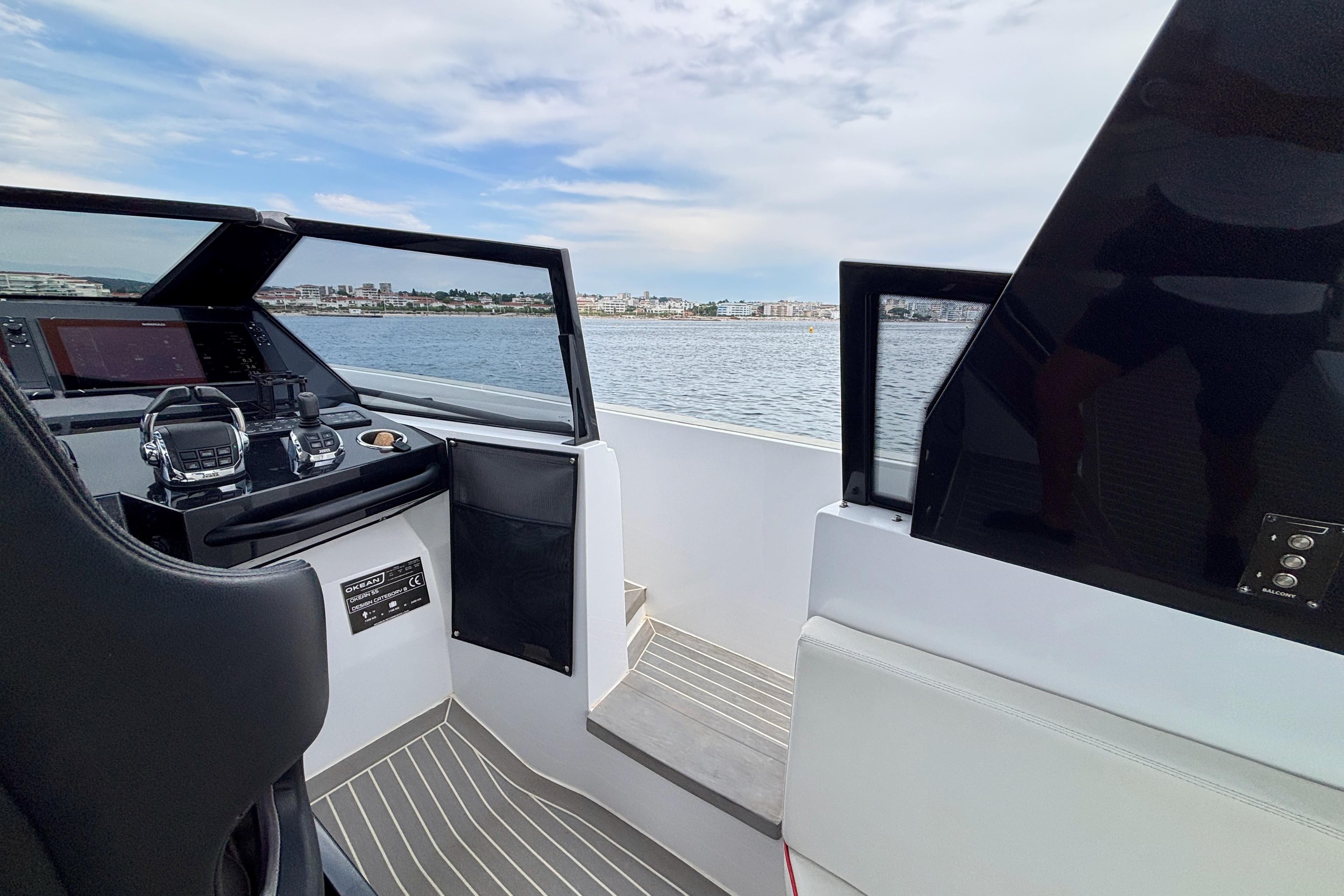 Cockpit view of 2021 OKEAN 55 yacht, featuring modern controls and ocean backdrop.