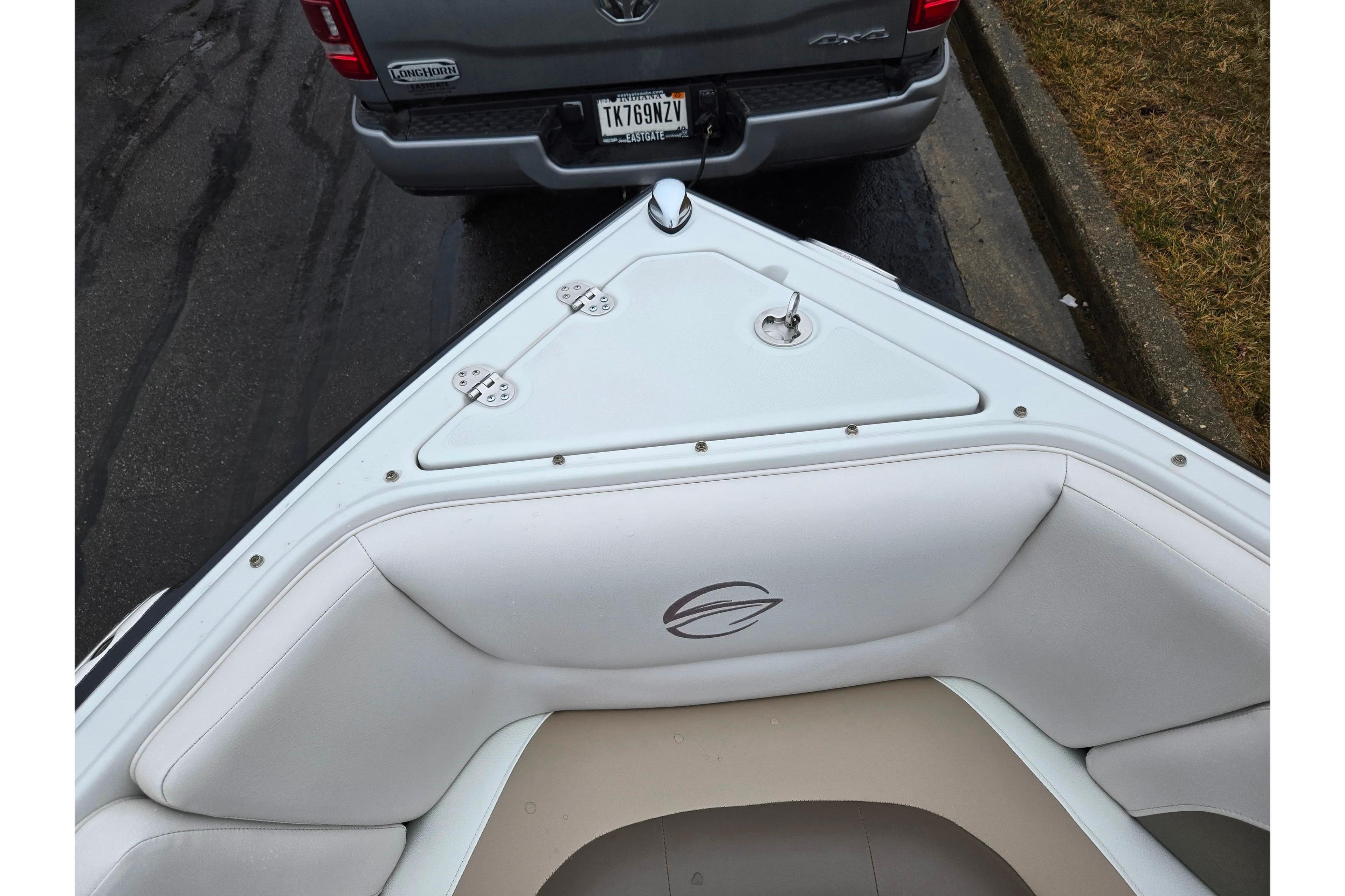 2012 Crownline 235 SS boat bow with white seating, parked near a truck.
