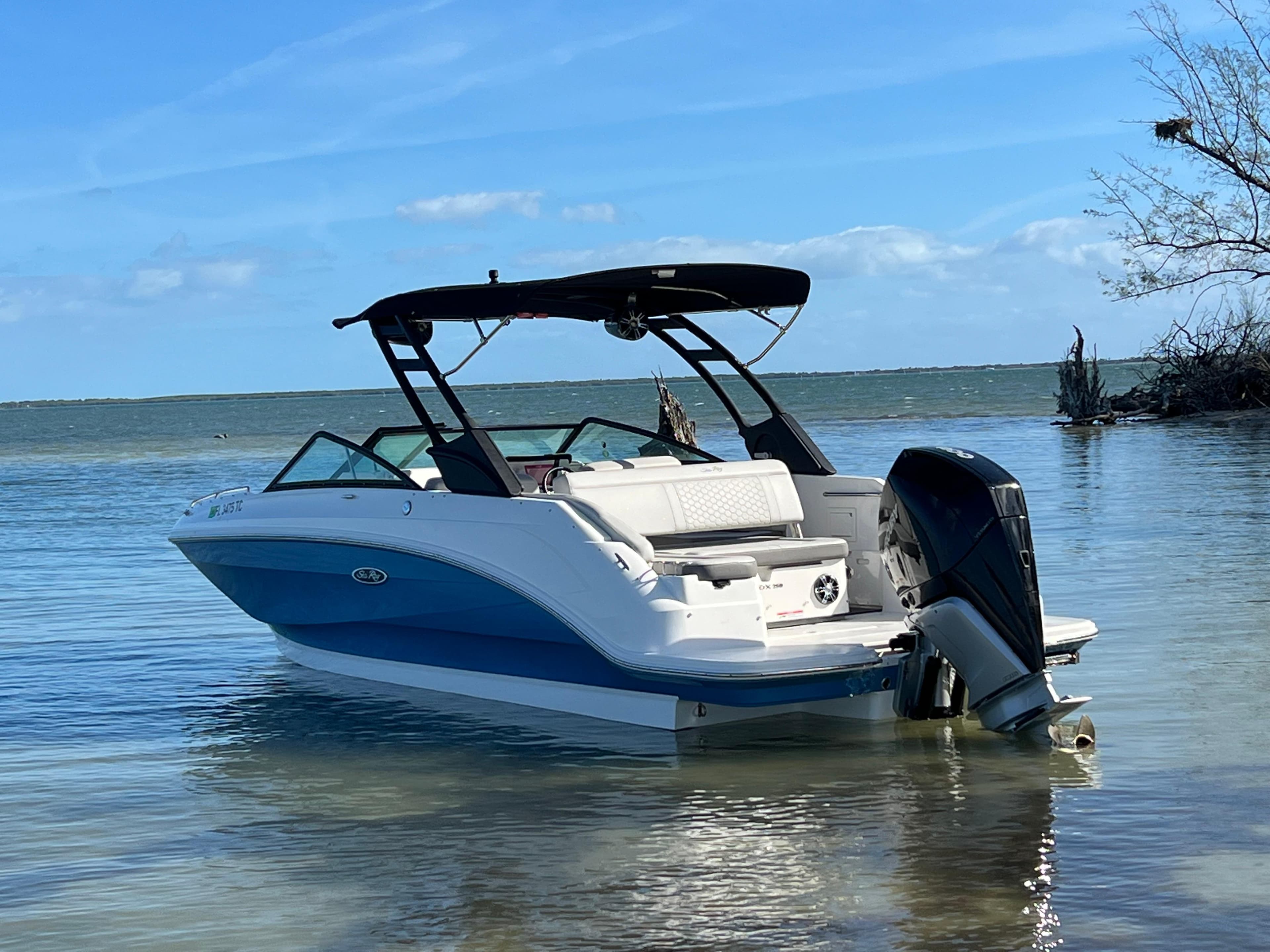 2022 Sea Ray 250 SDX-OB boat in shallow water, clear sky background.