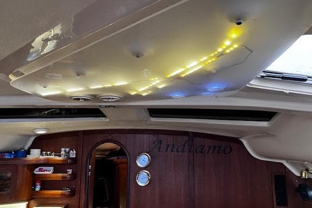 Interior of a 1996 Hunter 430 sailboat with illuminated ceiling and wooden cabinetry.