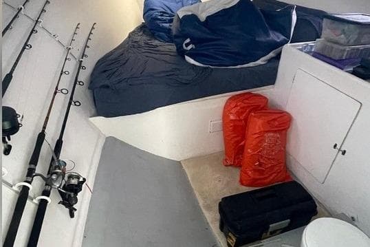 Interior of 1977 JC 31 Casco Bay boat with fishing rods and sleeping area.