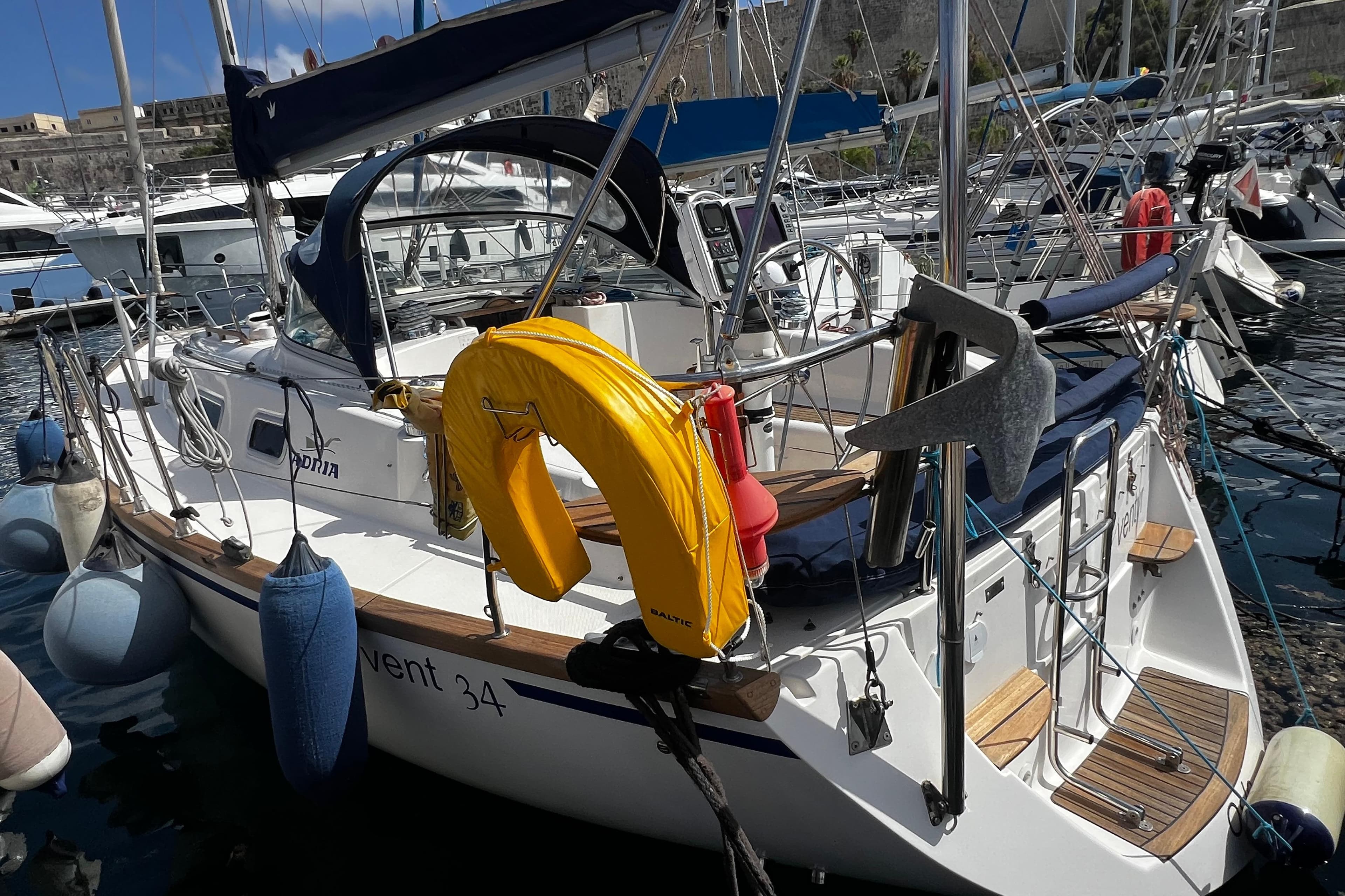 2004 Adria Event 34 sailboat docked in marina, featuring yellow life preserver and anchor.