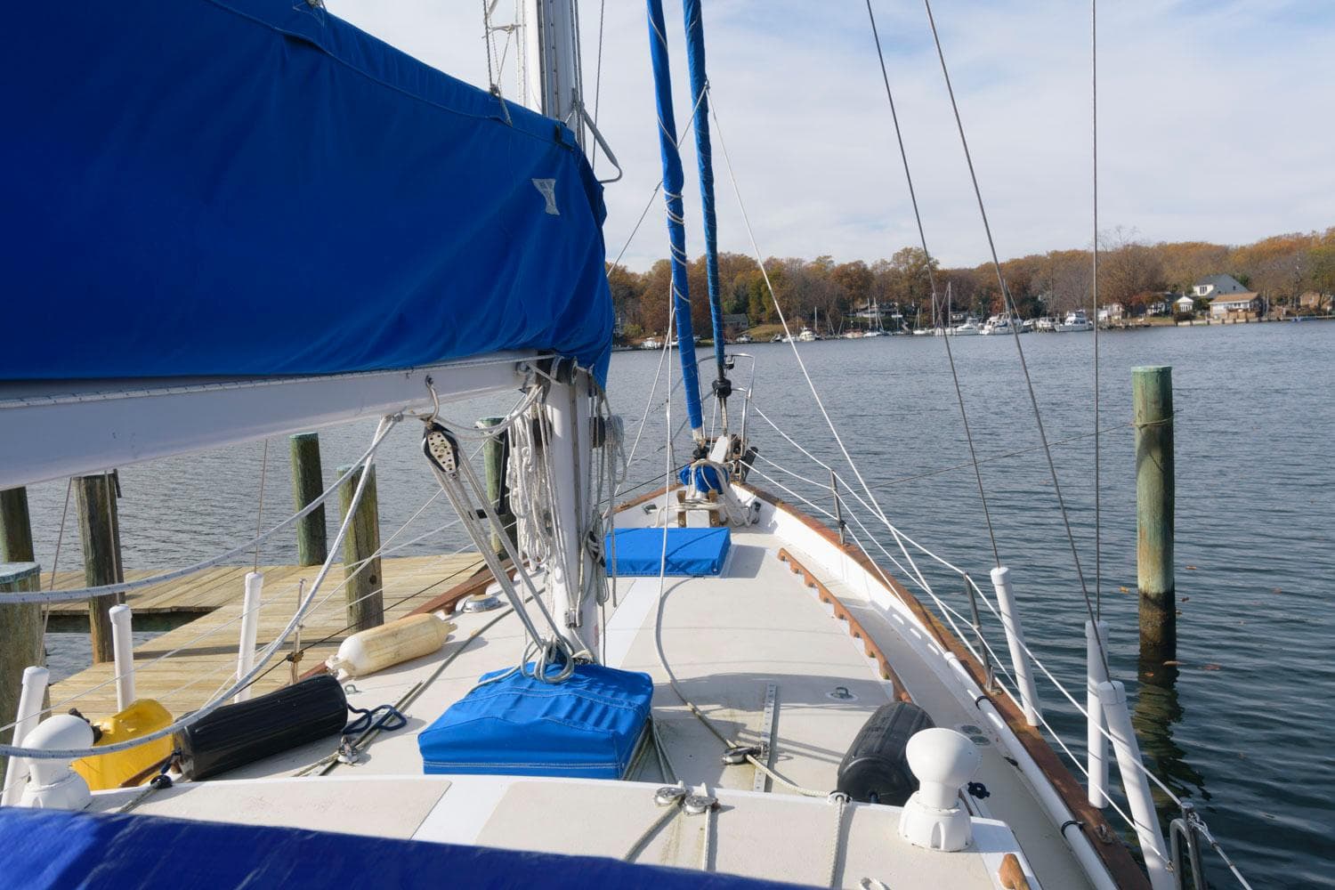 1976 Downeast 38 sailboat docked at a marina with blue sail covers.