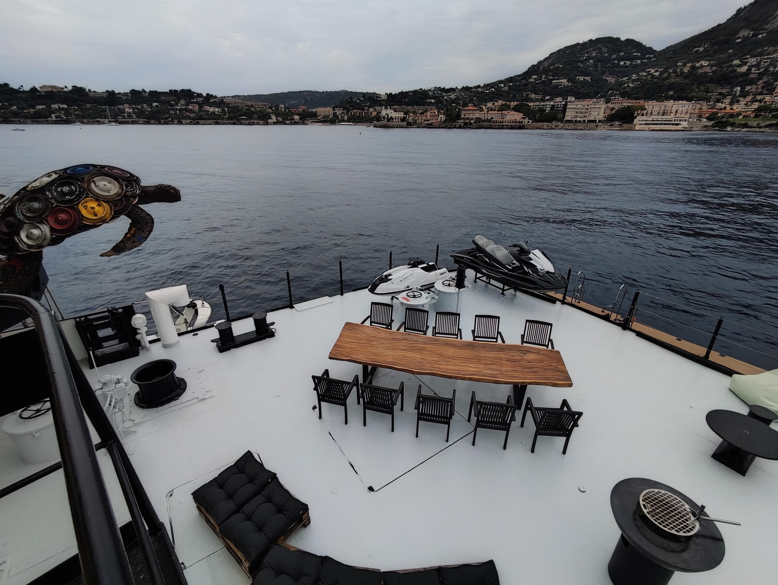 Luxurious yacht deck with dining area, overlooking serene waters and coastal hills, Custom Explorer 1985.