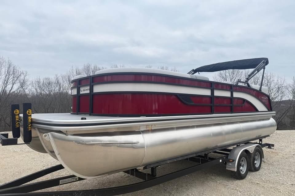 2026 Lowe SS 230 WV pontoon boat on trailer, red and silver design, parked outdoors.