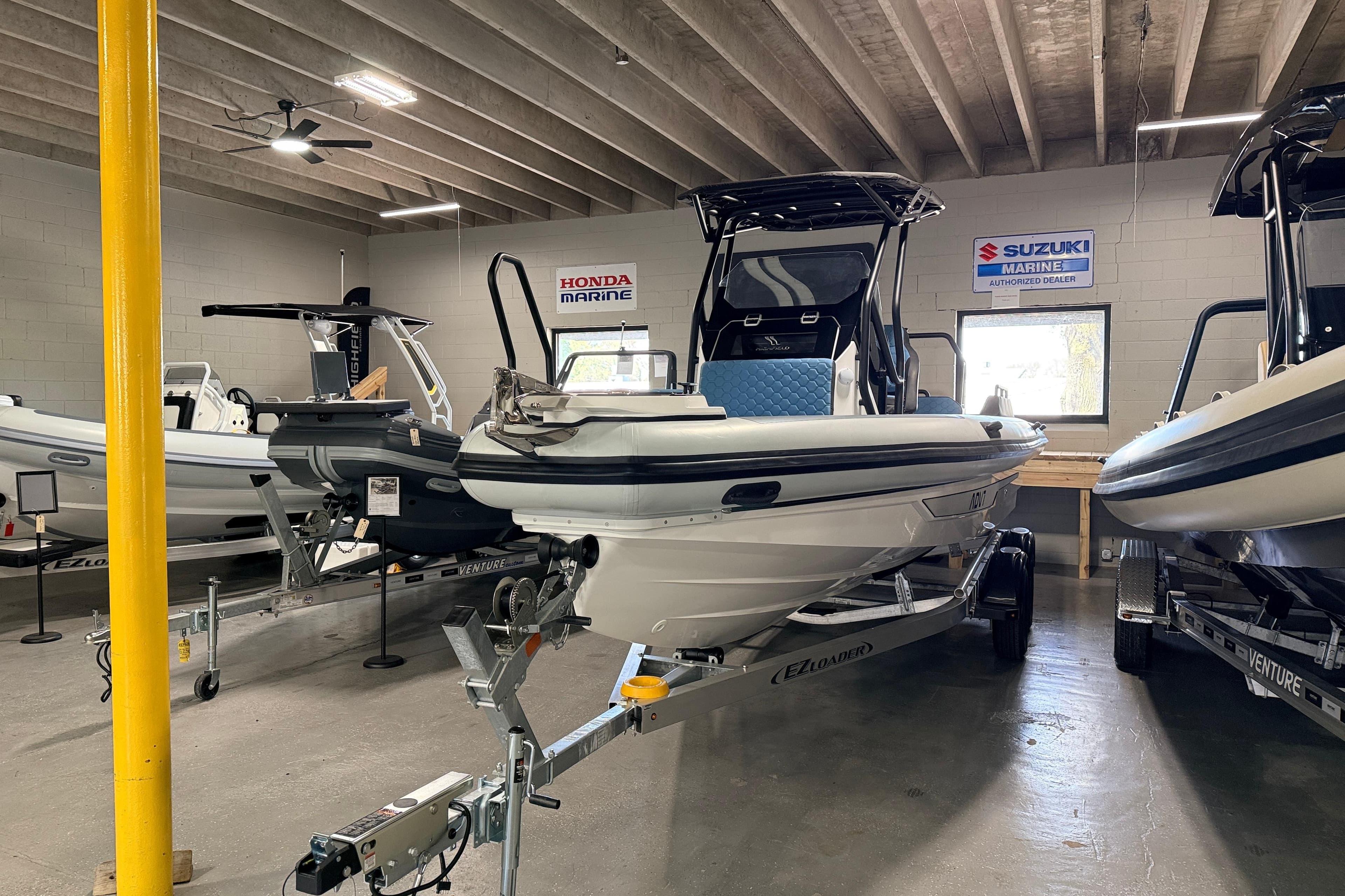 2026 Highfield ADV7 boat displayed in a showroom with Honda and Suzuki Marine signs.