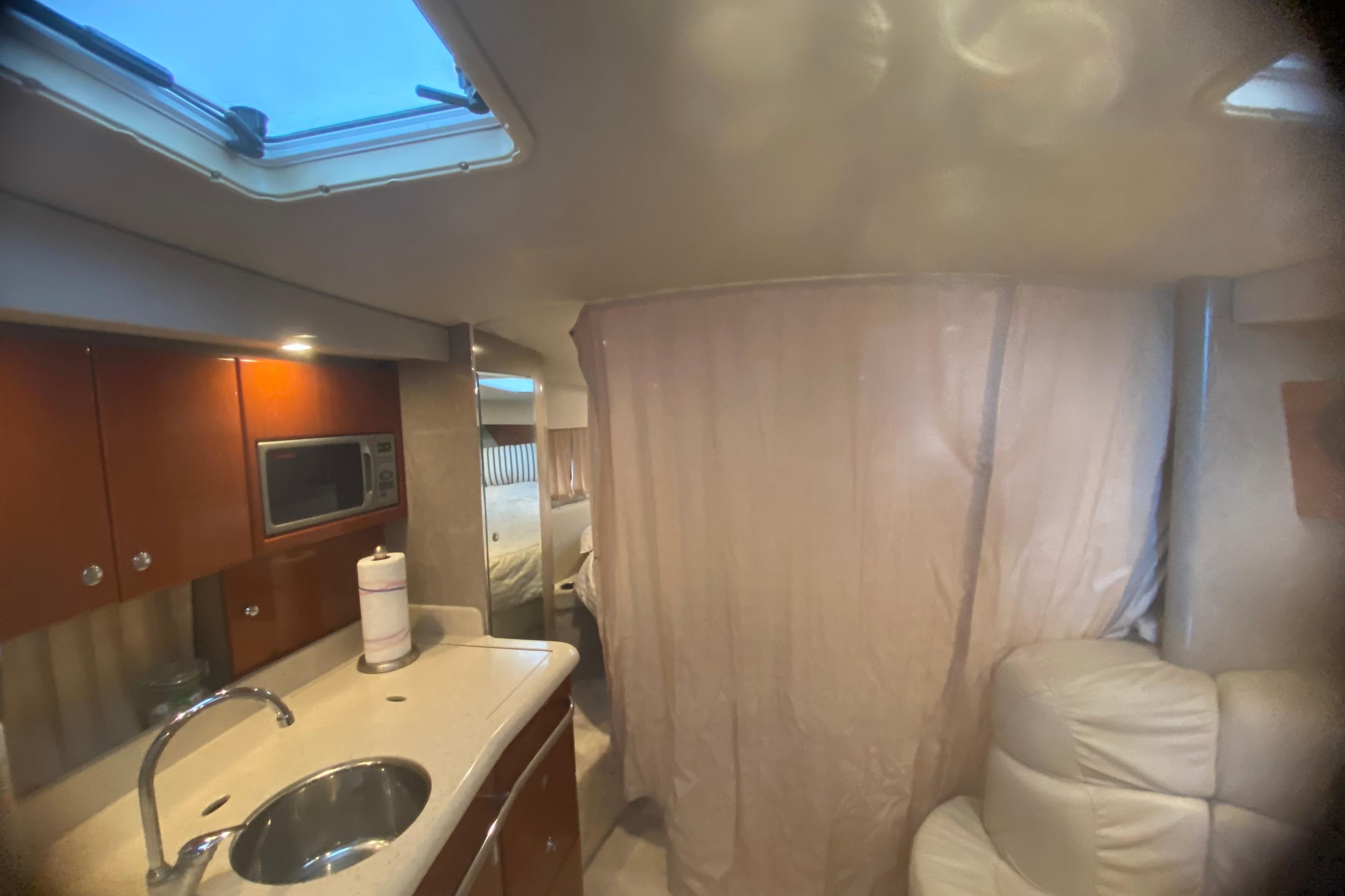 Interior of a 2005 Formula boat with kitchenette, sink, and seating area.