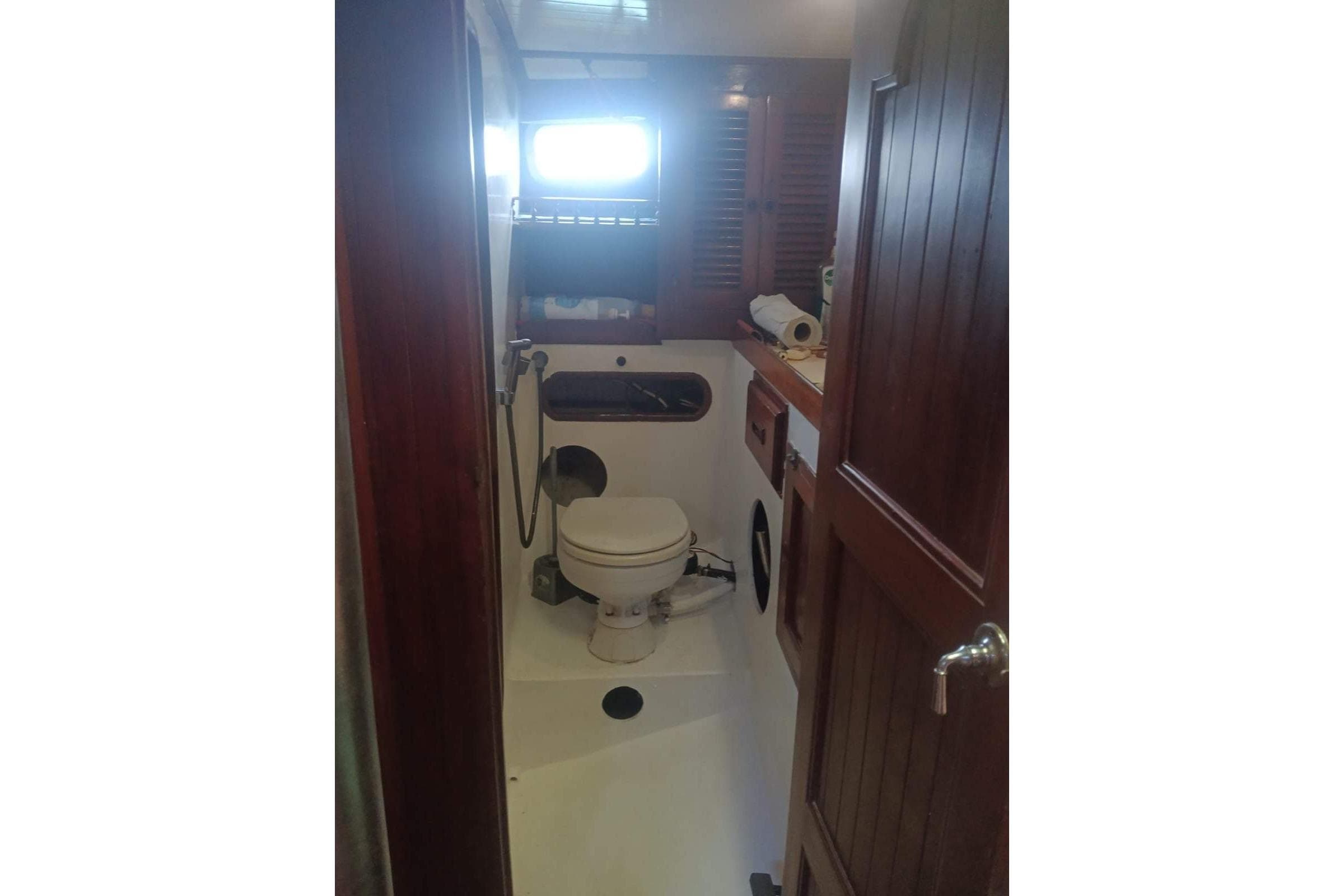 Bathroom interior of 1982 Vagabond 47 sailboat with wooden accents and compact design.
