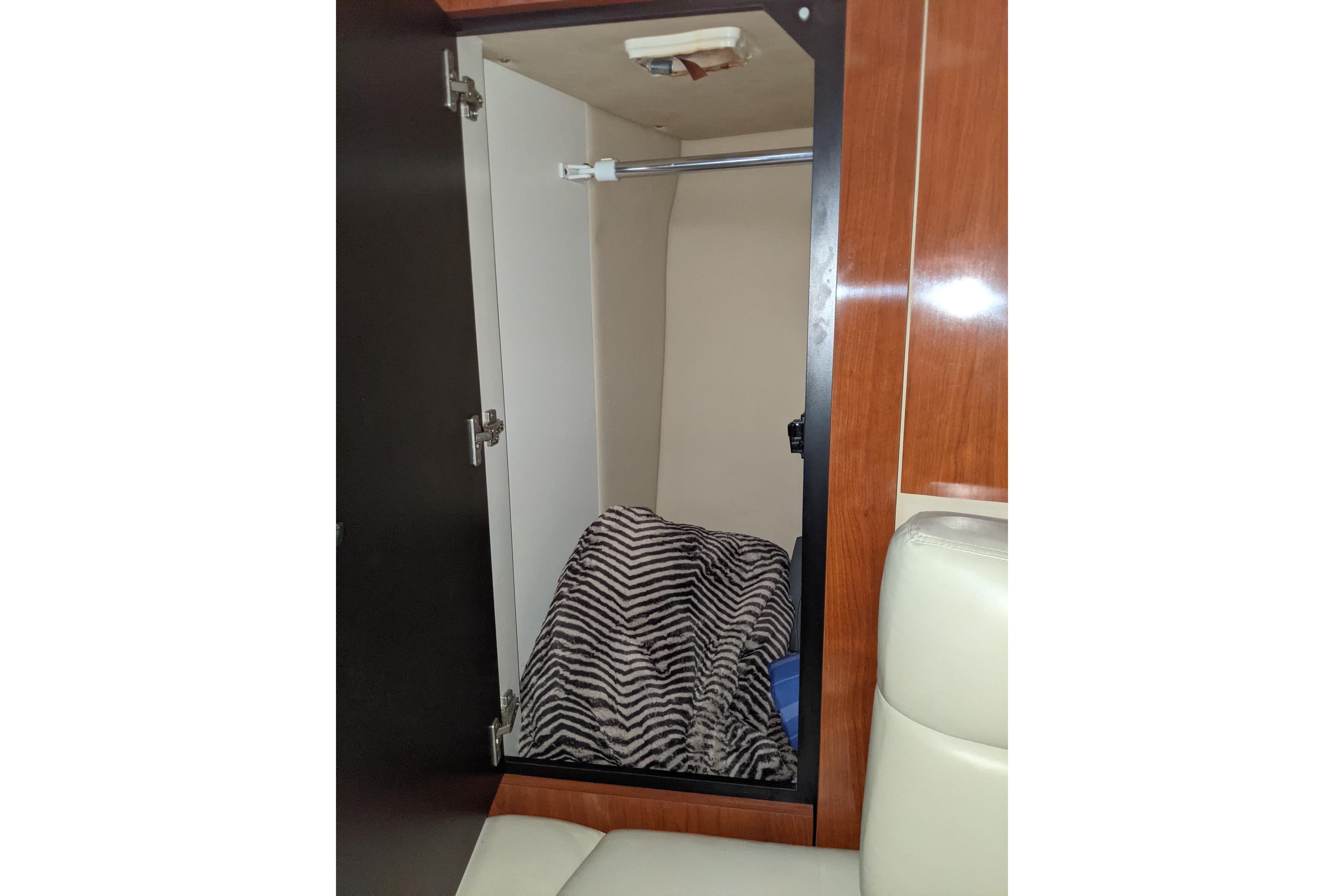 Open closet in 2004 Sea Ray 380 Sundancer with striped blanket inside.