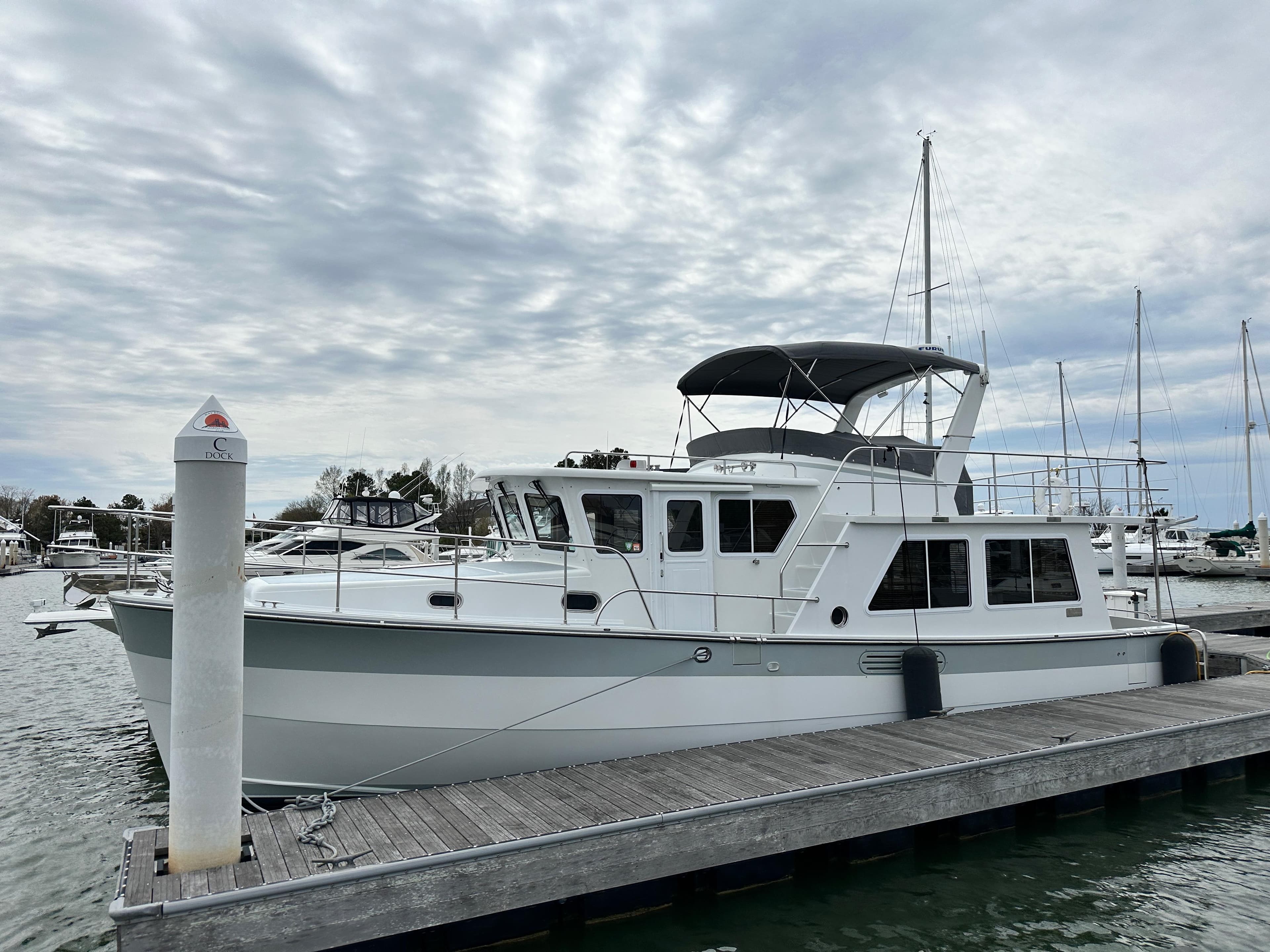 2023 Helmsman Trawlers 43E Pilothouse docked at a marina under cloudy skies.