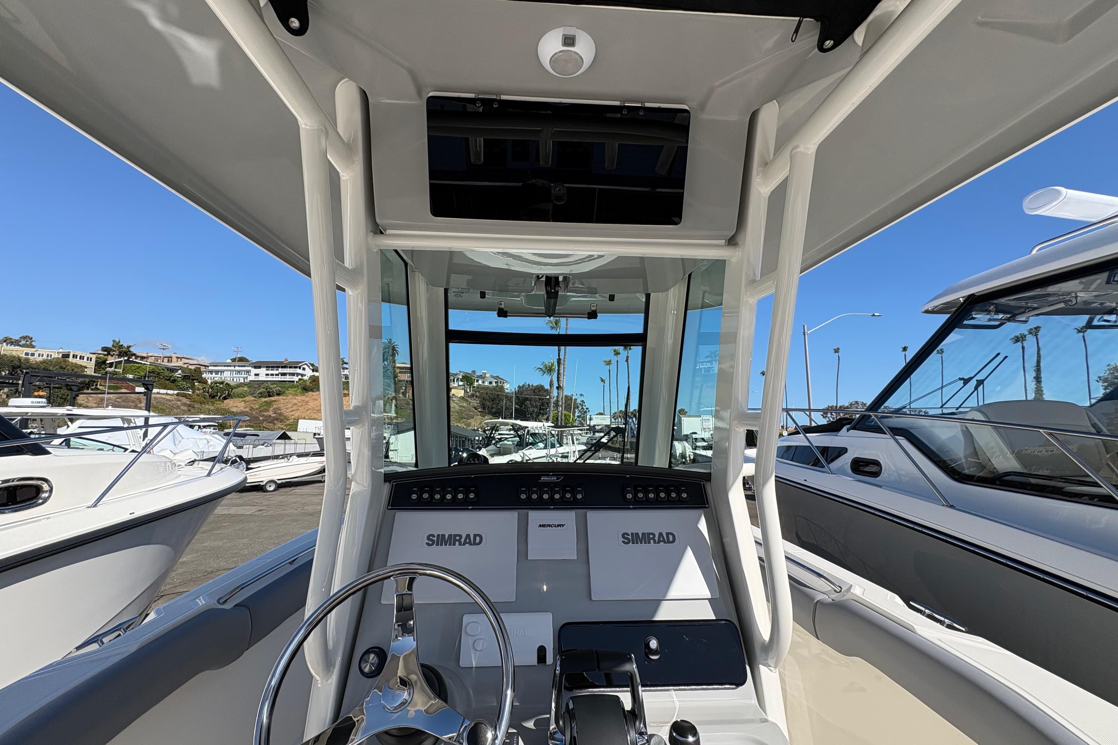 2026 Boston Whaler 280 Outrage boat cockpit with Simrad navigation system, docked in marina.