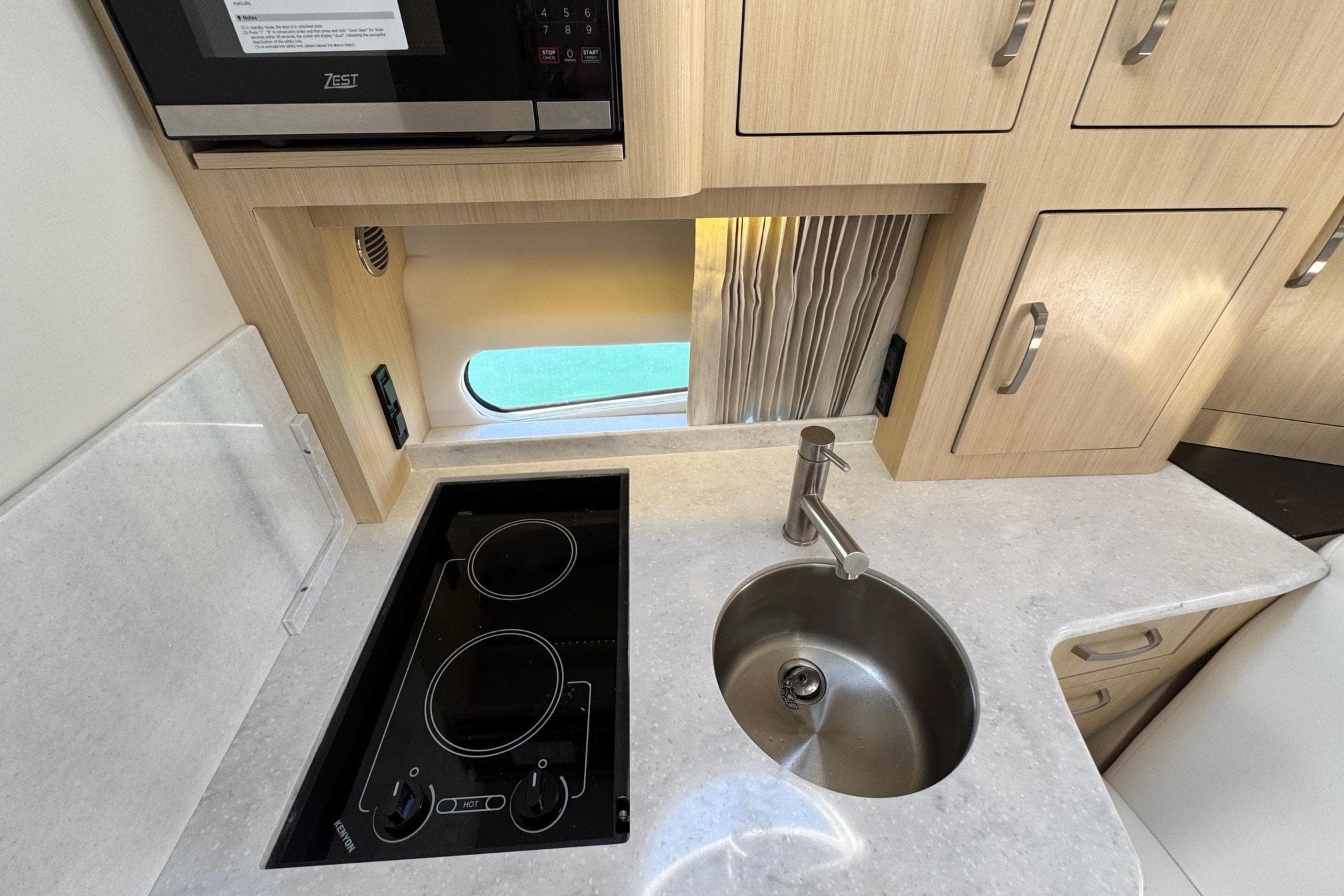 2026 Regal 33 XO yacht kitchen with stove, sink, and wooden cabinetry.