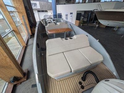 2023 Rand Source 22 boat interior with beige seating and wooden flooring in showroom.