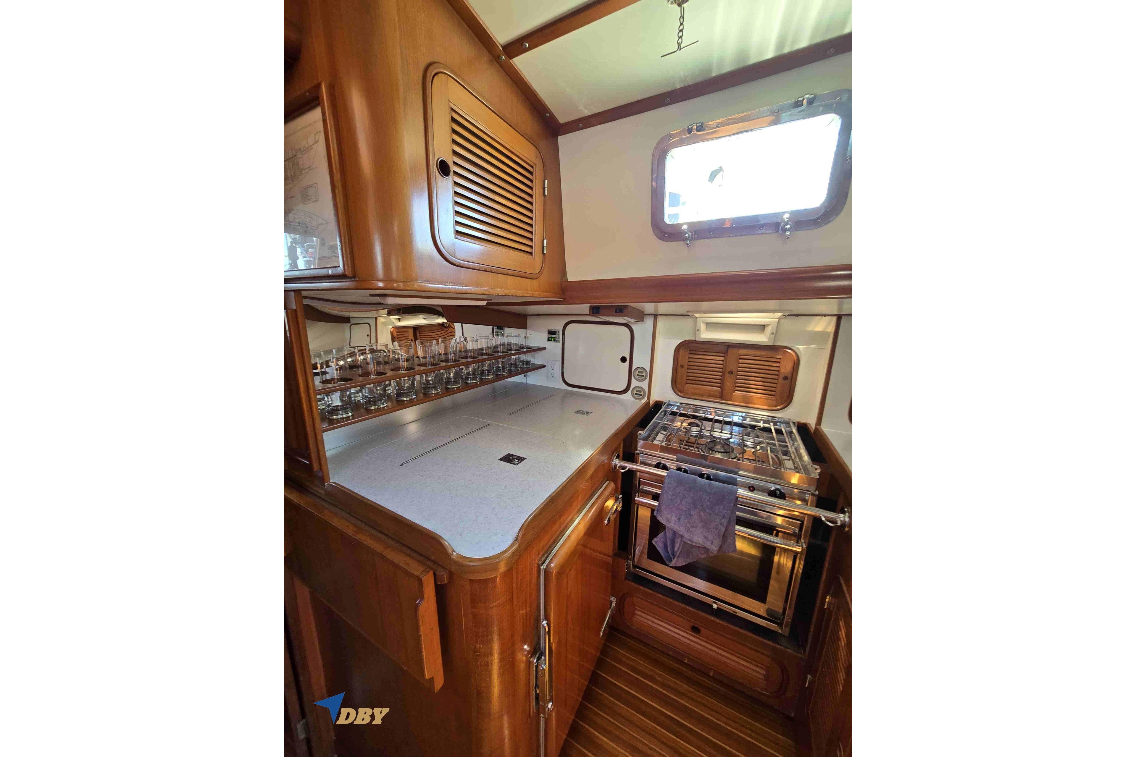 Vintage 1983 Mason 53 yacht kitchen with wooden cabinetry and stainless steel stove.