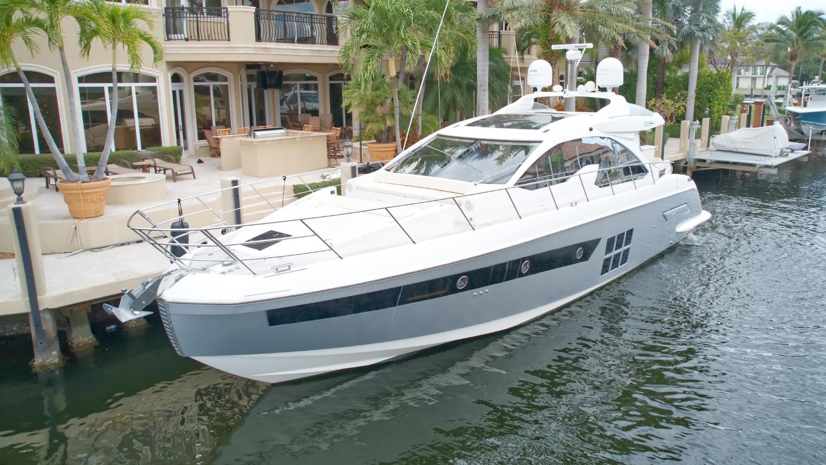 2013 Azimut 55S luxury yacht docked by waterfront mansion.
