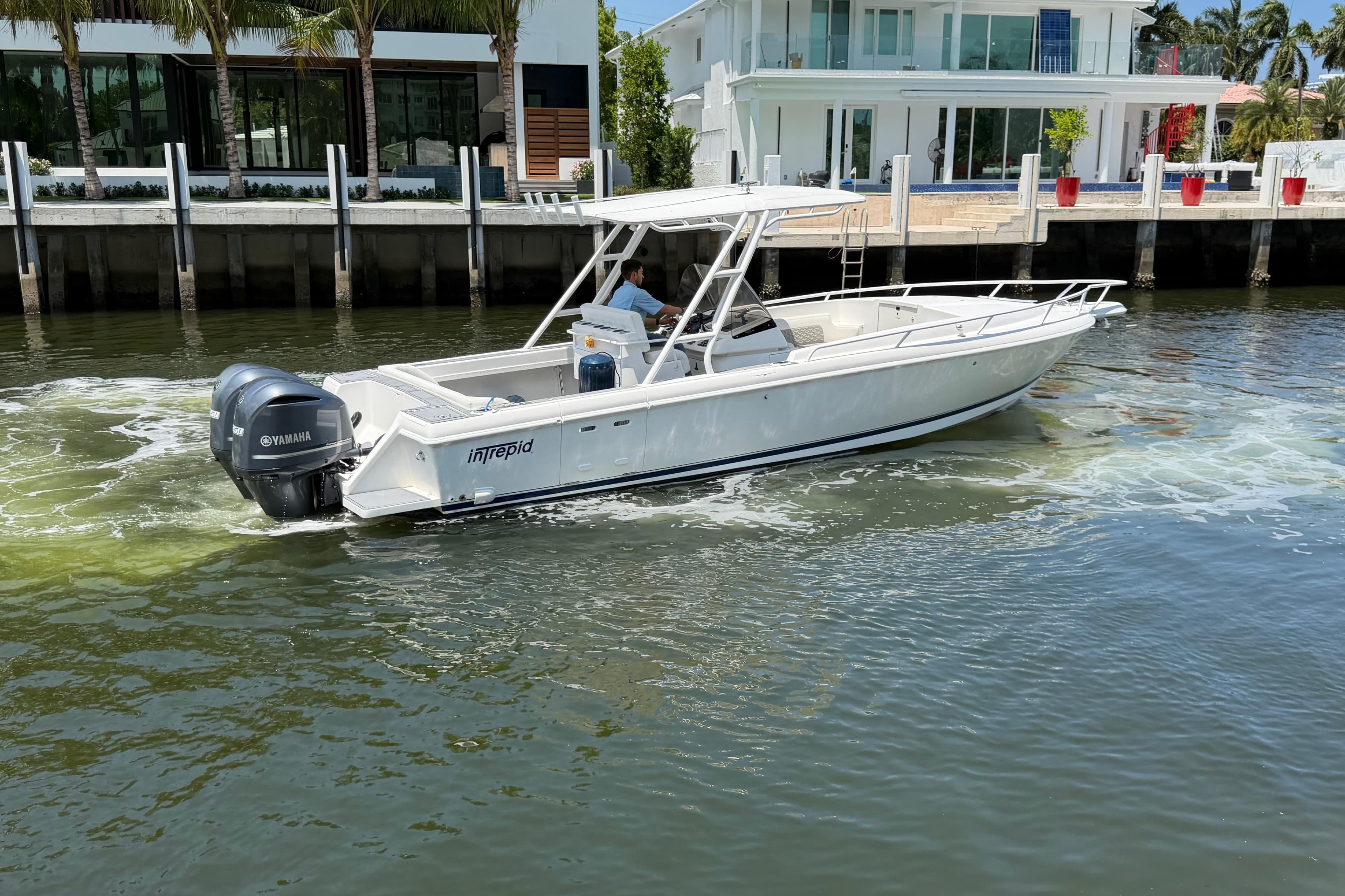 2003 Intrepid 323 Cuddy boat cruising near waterfront homes.