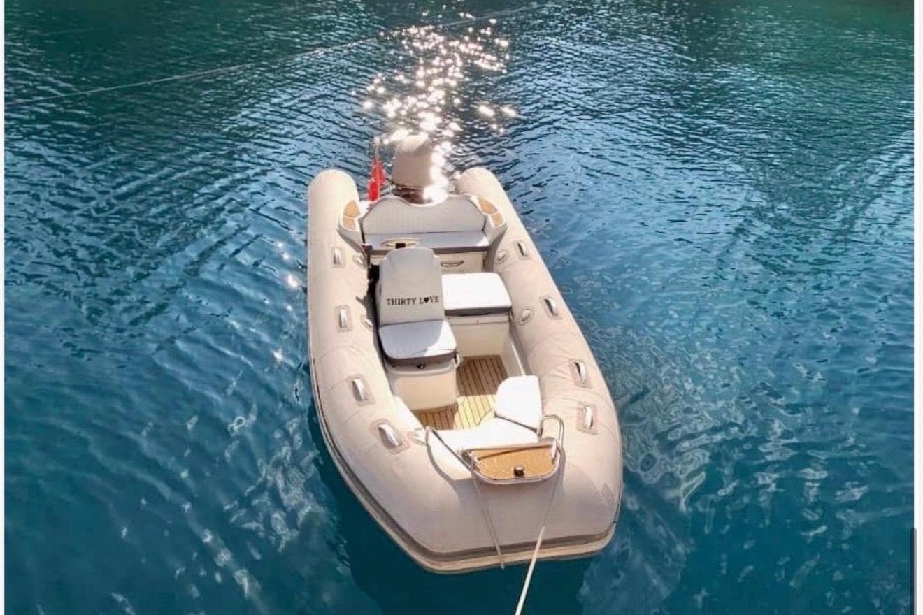 Inflatable boat on clear blue water, sunlight reflecting; Cantieri di Pisa Akhir 30S, 1992 model.