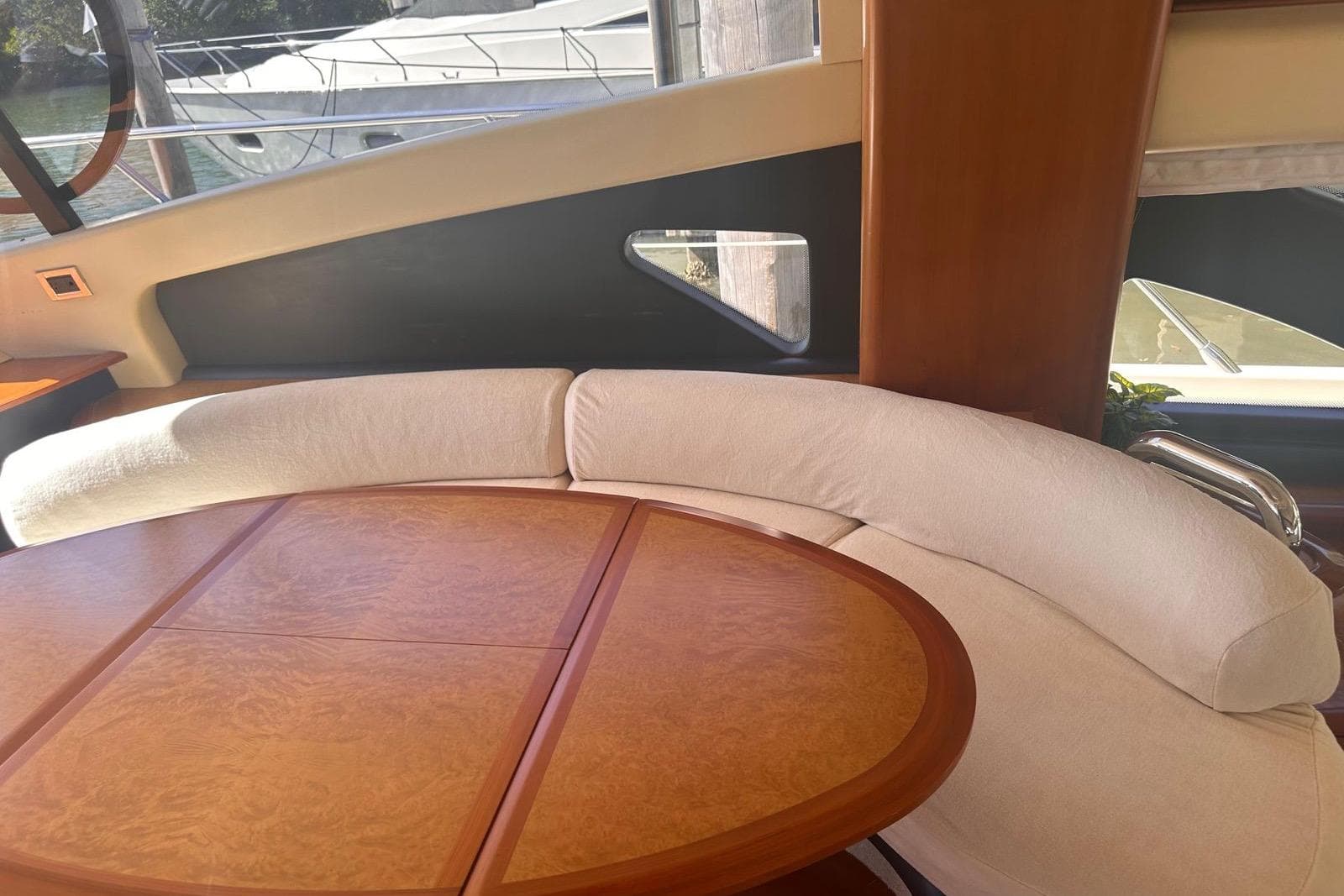 Luxurious interior of a 2007 Azimut 55E yacht with elegant wood table and curved seating.