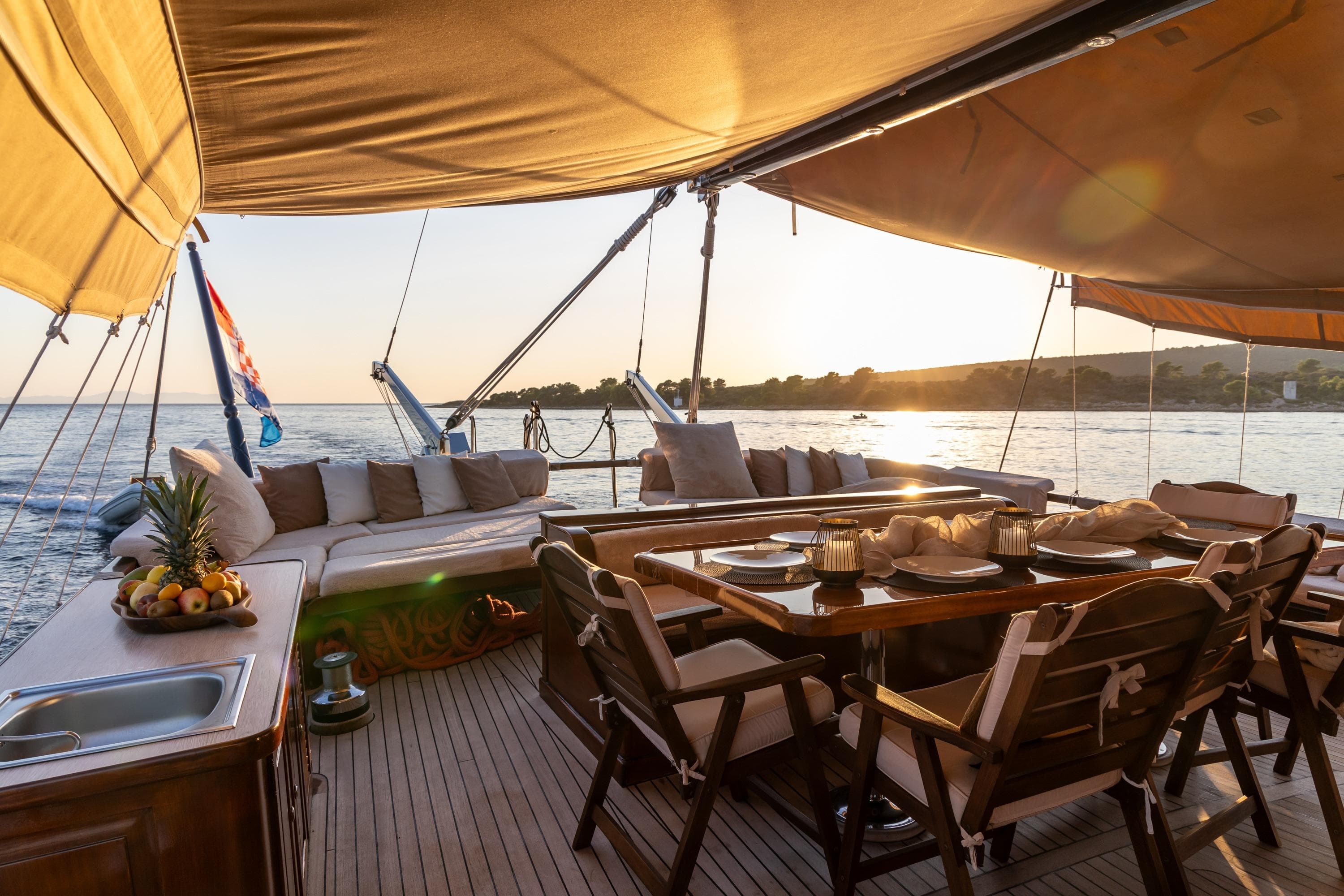 Luxurious 2000 Custom GULET yacht deck with dining area at sunset, featuring elegant seating and fruit display.