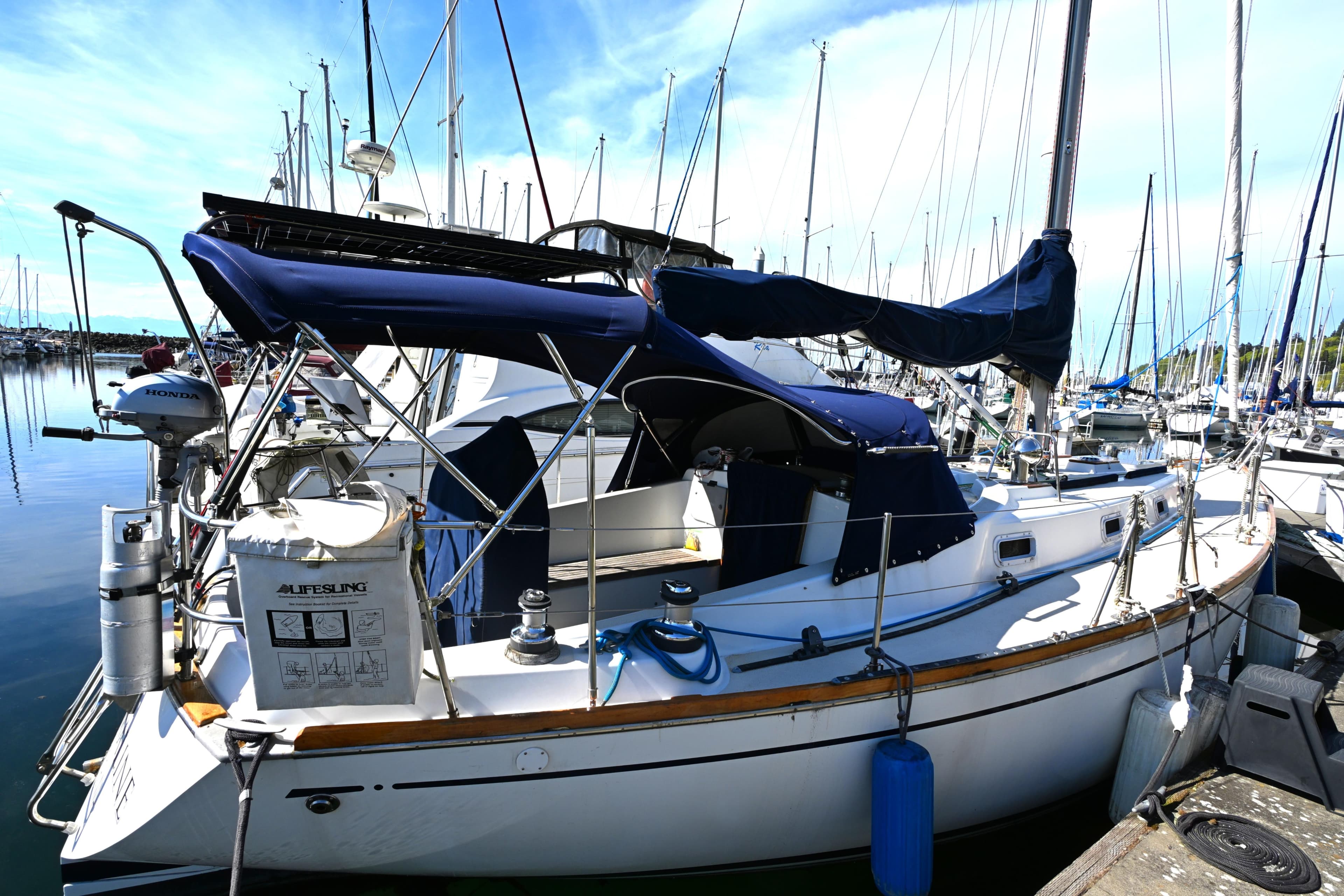 1980 Tartan 37 sailboat docked in a marina, featuring blue covers and lifebuoy.