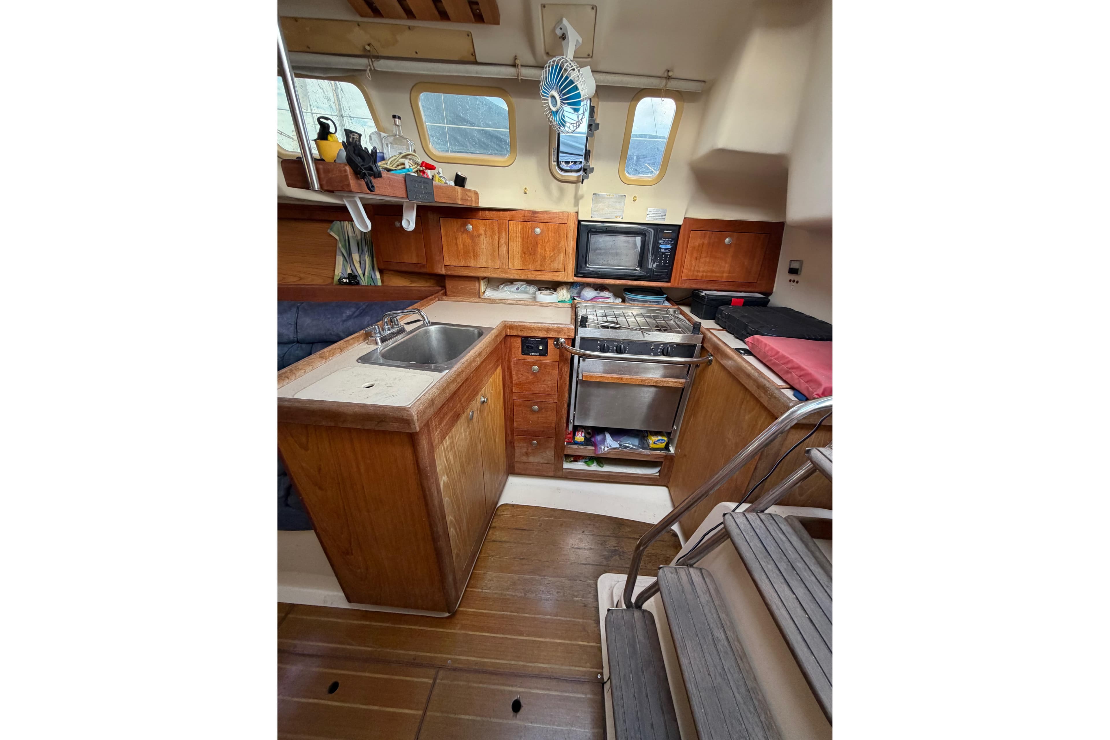 Interior of a 2000 Hunter 310 sailboat kitchen with wooden cabinetry and appliances.