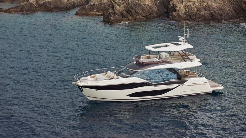 Luxury yacht Prestige F5.7, 2026 model, cruising near rocky coastline.