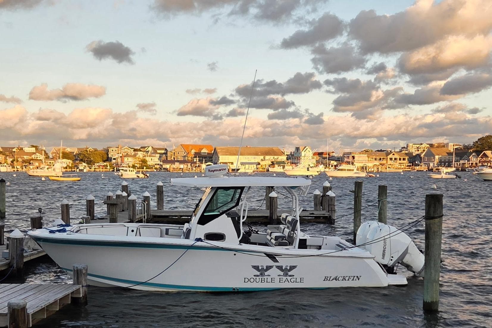 2018 Blackfin 272 CC boat docked at a scenic harbor with cloudy sky.