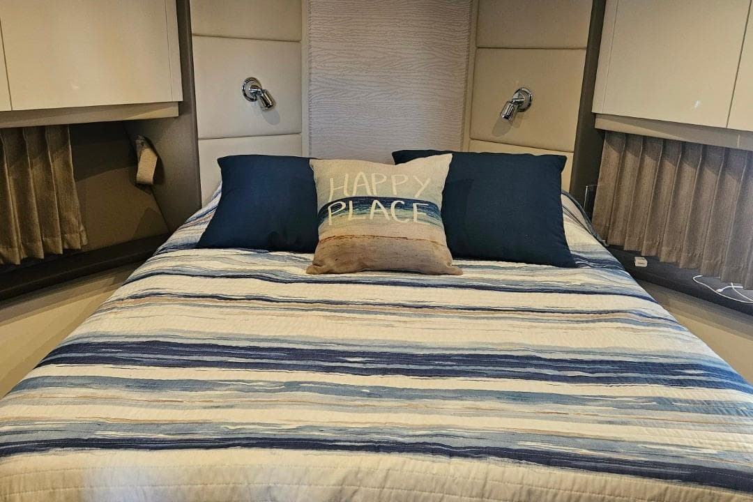Cozy bedroom in 2020 Carver C37 Coupe with striped bedding and decorative pillows.