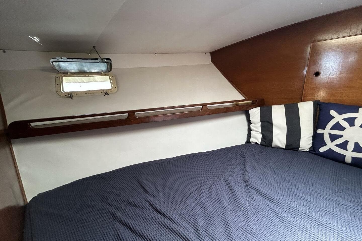 Cozy cabin interior of 1984 Hatteras 36 Convertible with nautical-themed pillows.