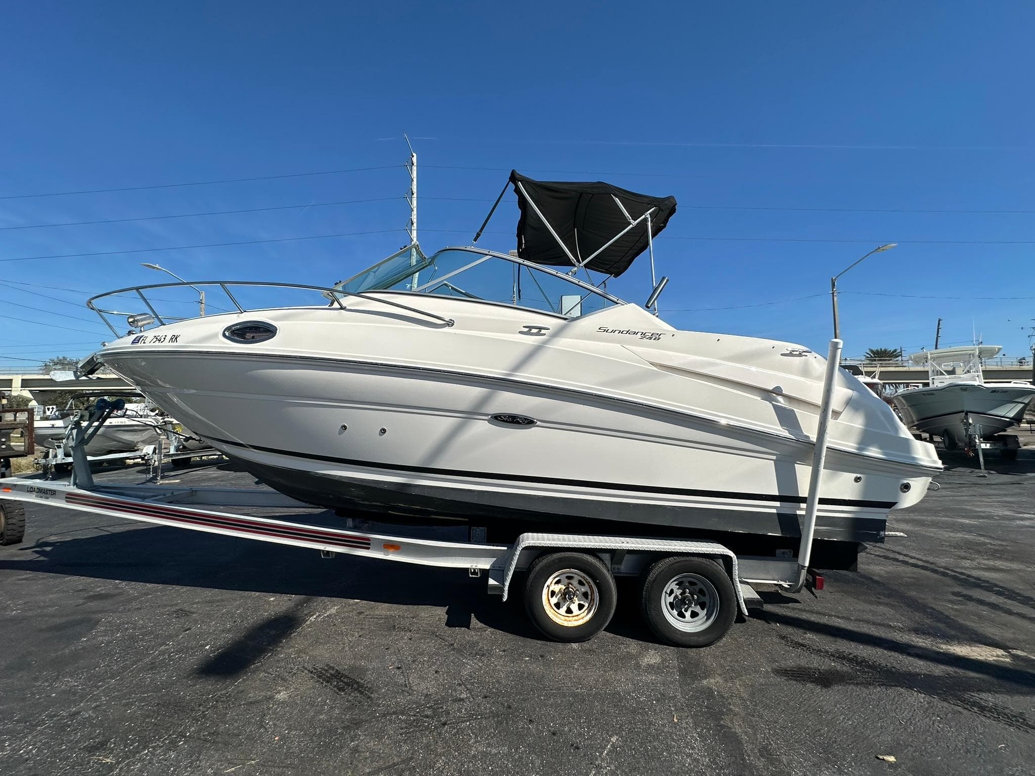 2010 Sea Ray 240 Sundancer boat on trailer, parked outdoors under clear blue sky.