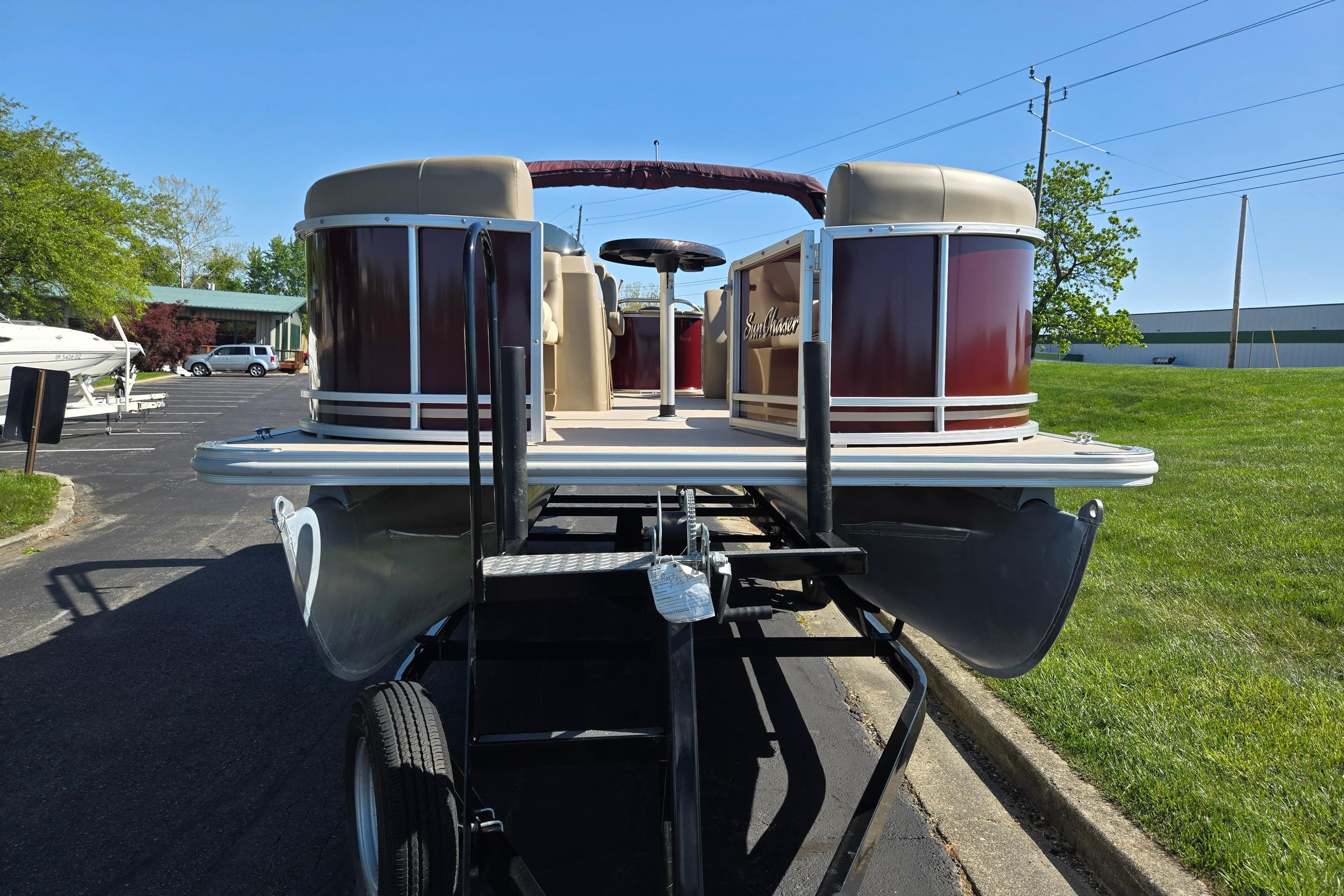 2023 SunChaser Geneva Fish 22 pontoon boat on trailer, parked outdoors.