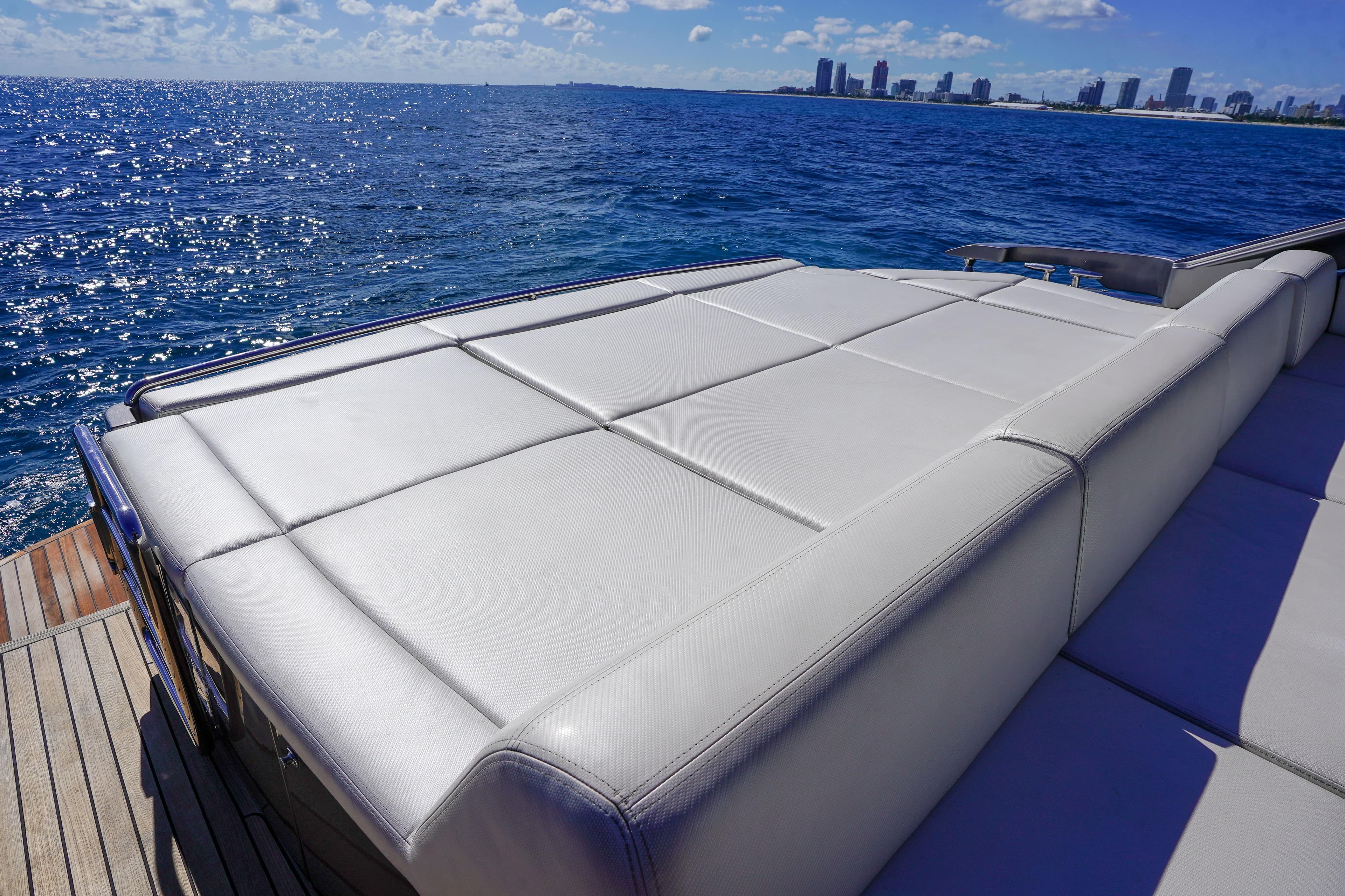 Luxurious 2019 Pershing 5x yacht with spacious sunbed, ocean view, and city skyline.
