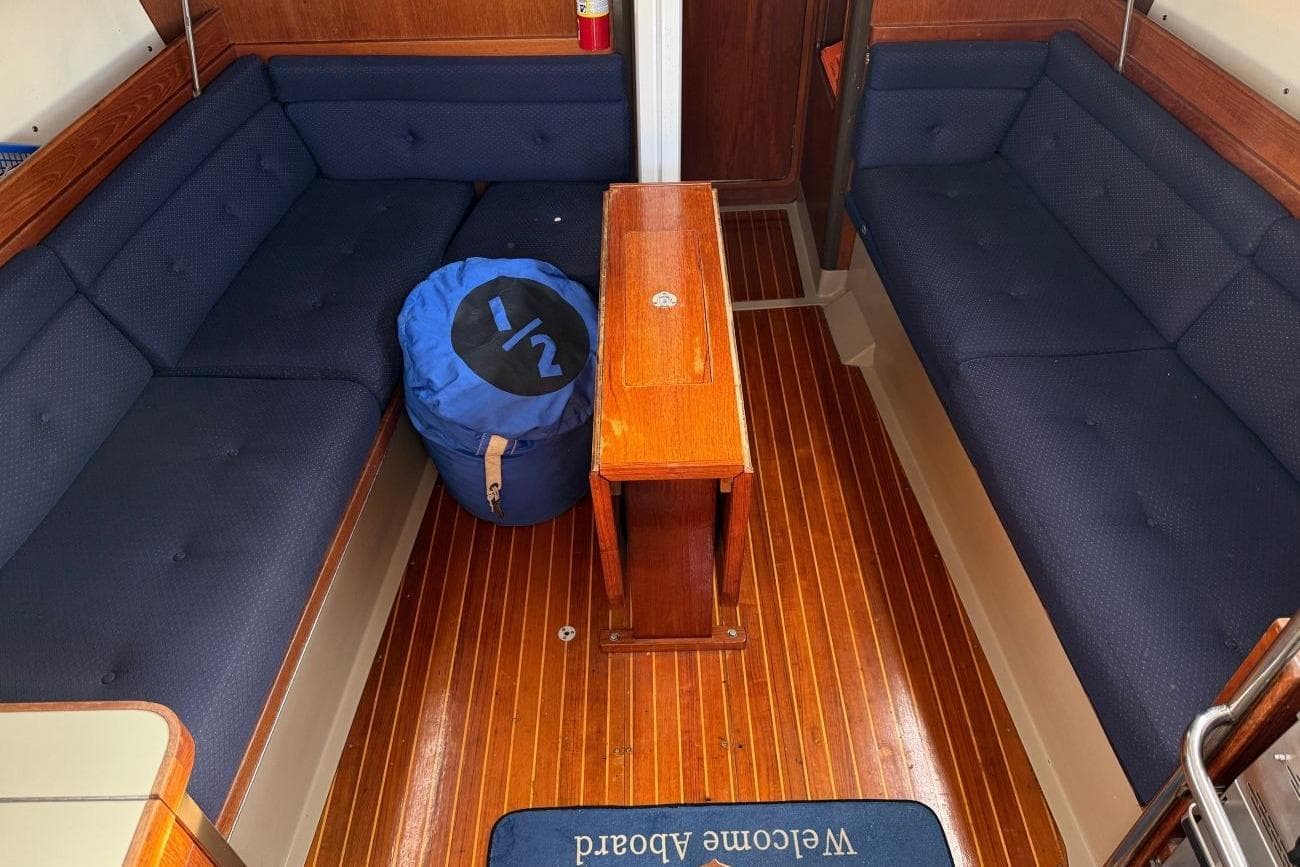 Interior of 1985 C&C 332 Sloop with blue seating and wooden table.