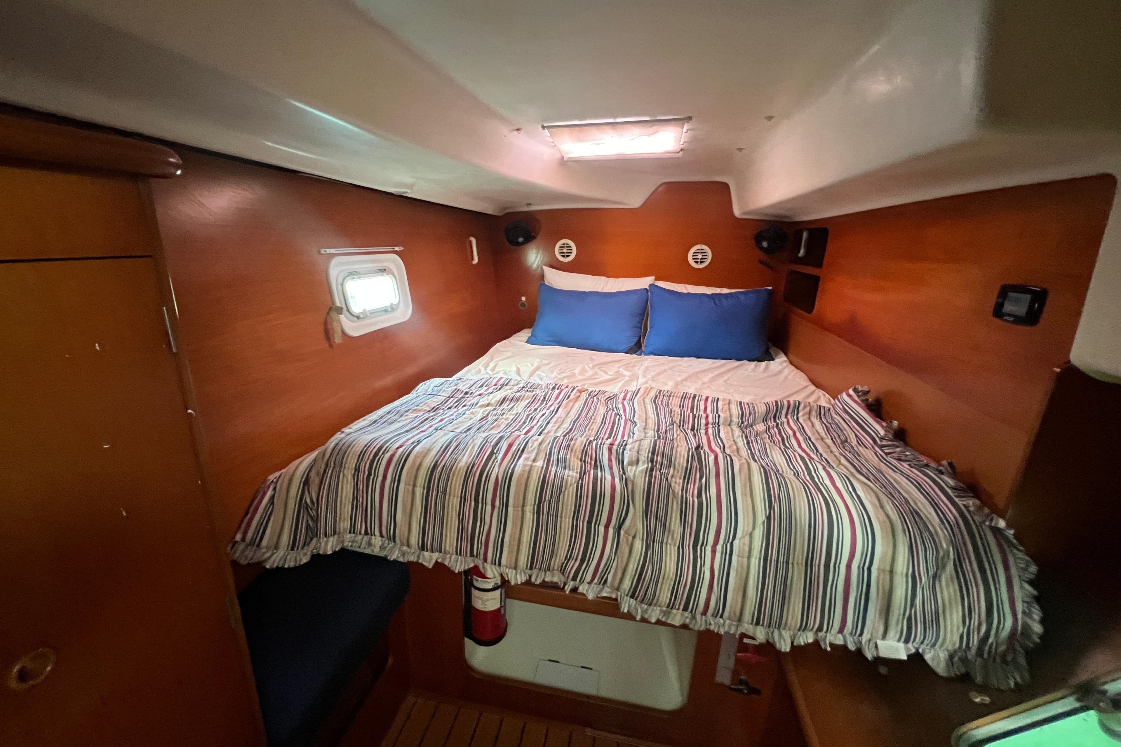 Cozy cabin interior of 2003 Lagoon 380 catamaran with striped bedding and wooden finish.
