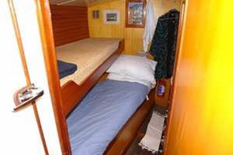Cozy cabin interior of 1980 Ketch Presles 72 with bunk beds and wooden paneling.