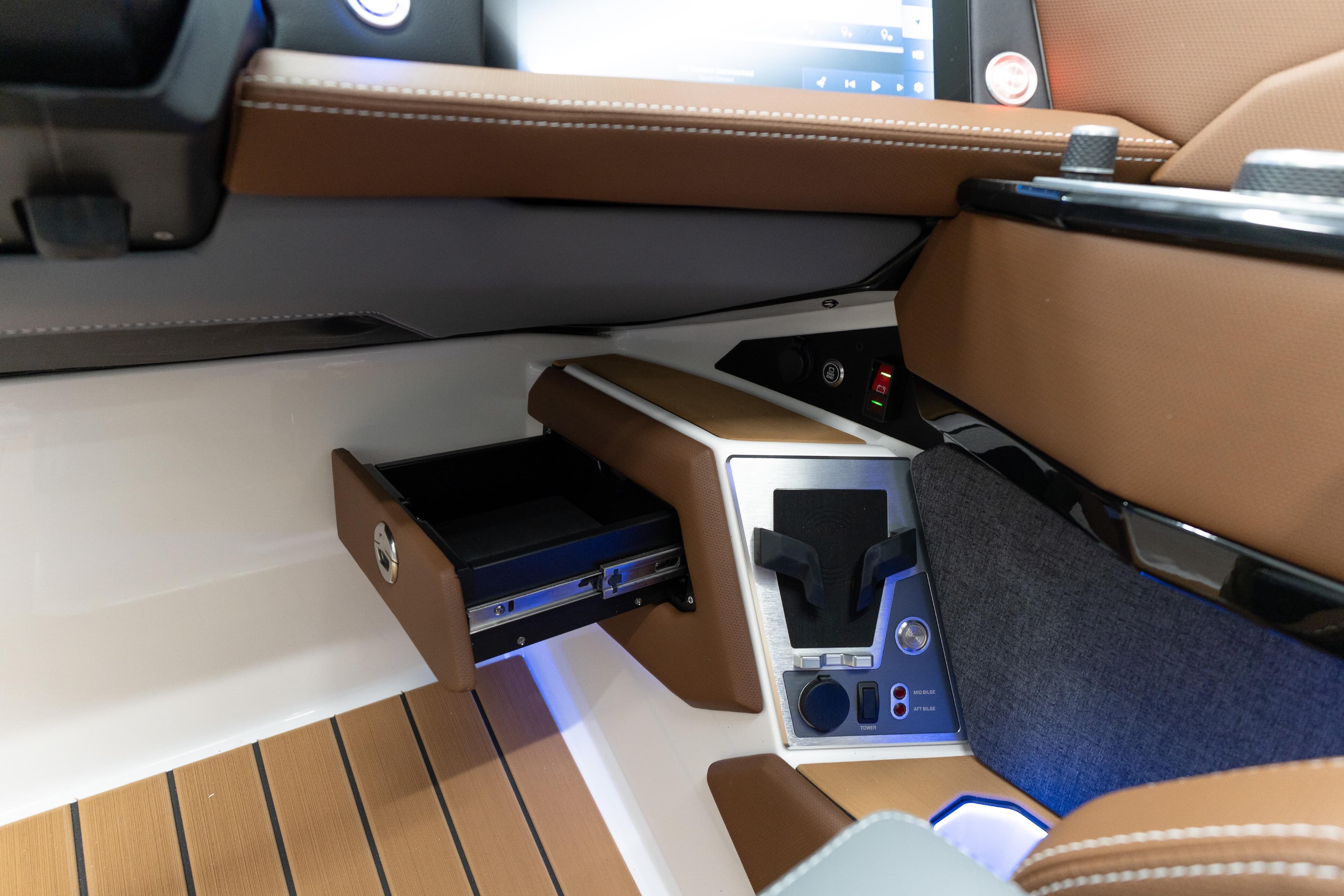 Interior of 2026 MasterCraft X24 boat with open storage compartment and control panel.