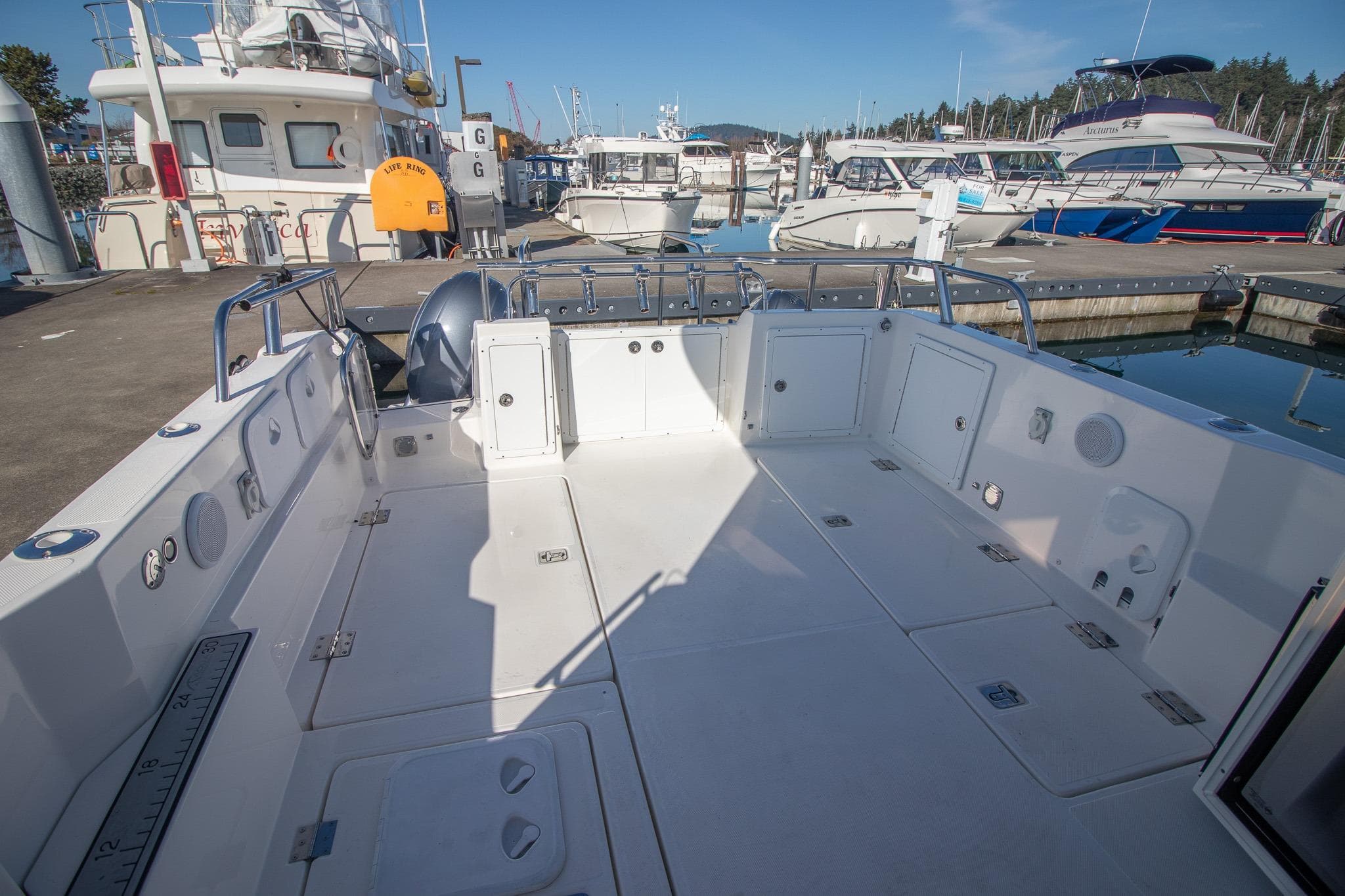 Spacious deck of 2022 Aspen C107 boat docked at marina under clear blue sky.