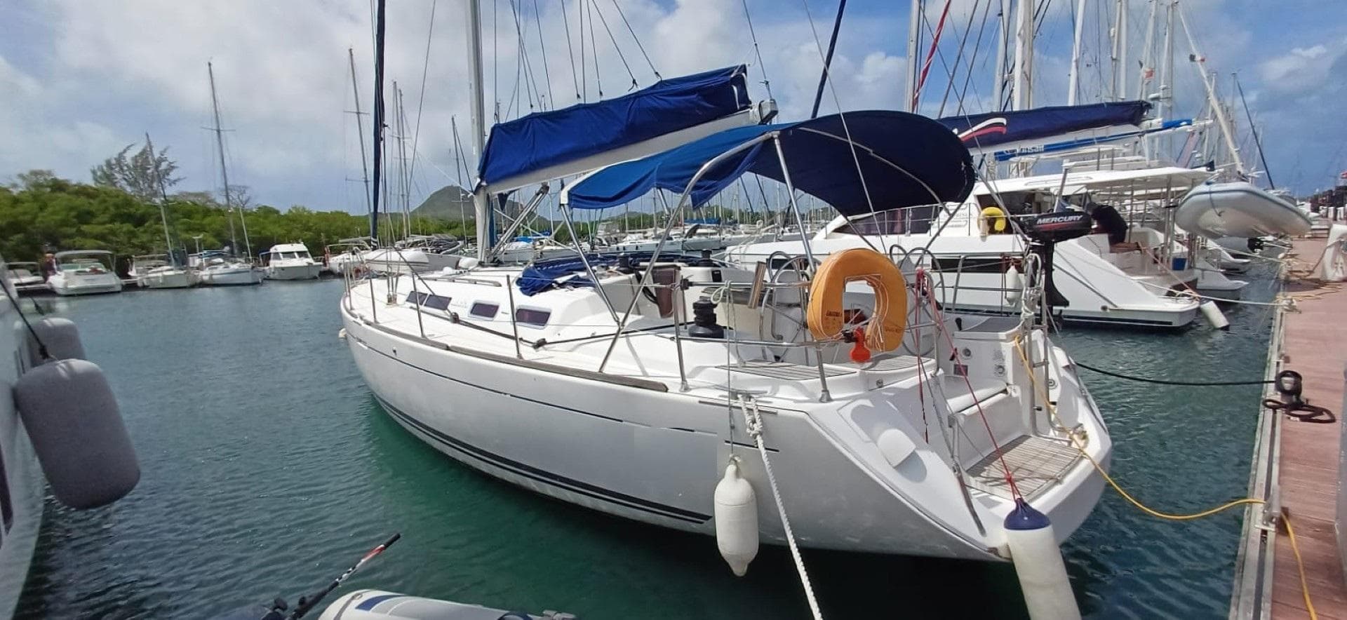2008 Dufour 455 Grand Large sailboat docked in a marina, featuring blue canopy and lifebuoy.