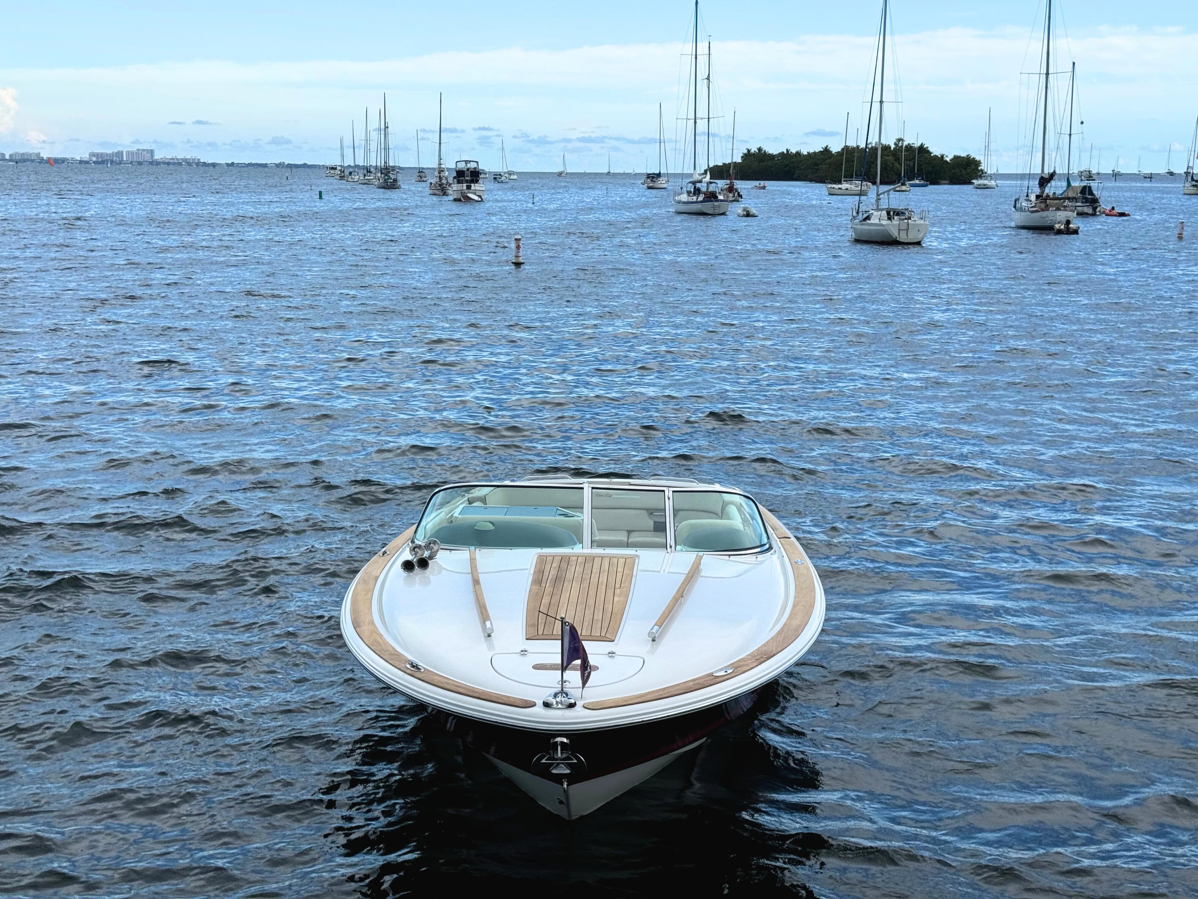 2004 Chris-Craft Corsair 28 boat on calm waters with sailboats in the background.