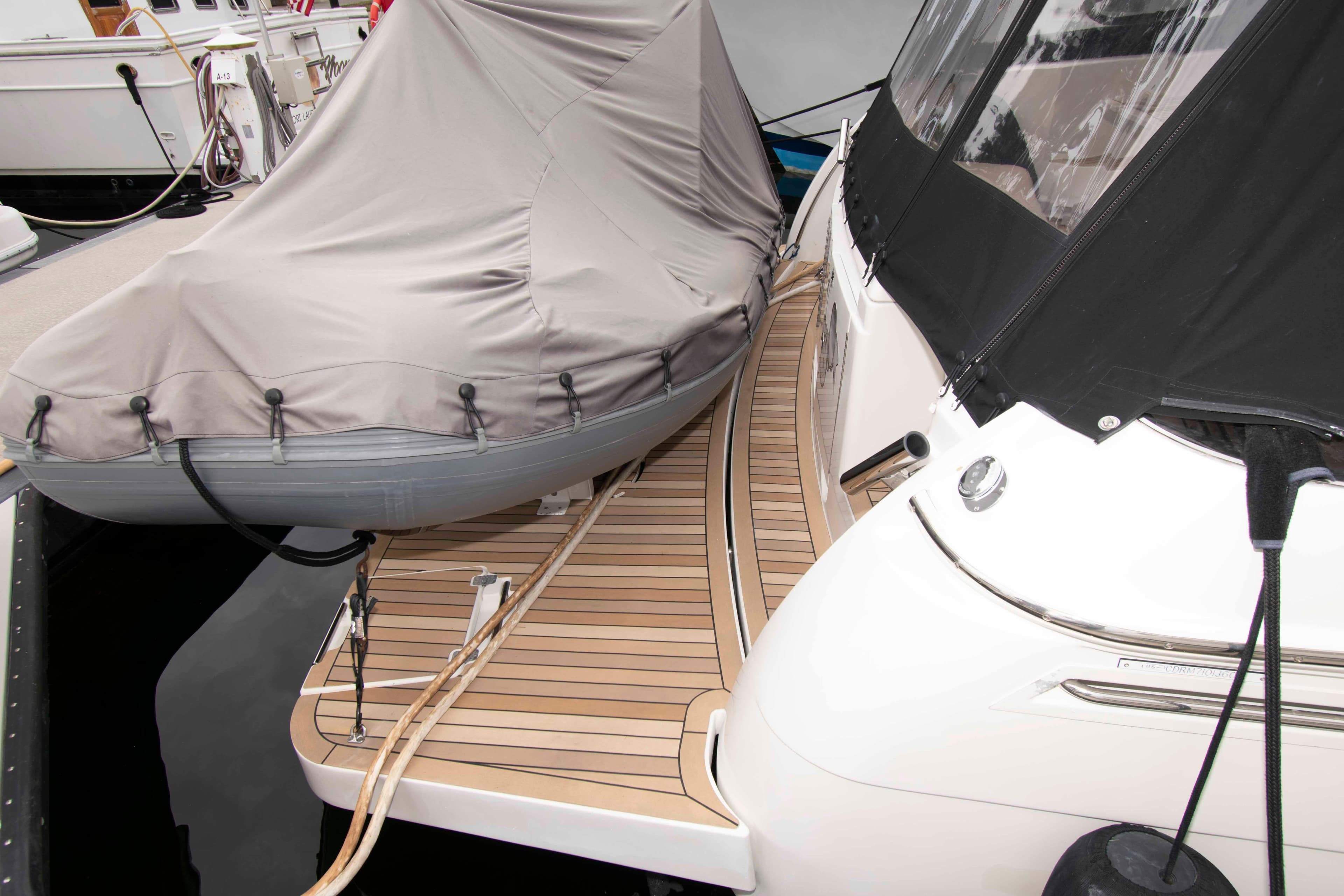 2007 Carver 56 Voyager yacht with covered dinghy on wooden deck at marina.