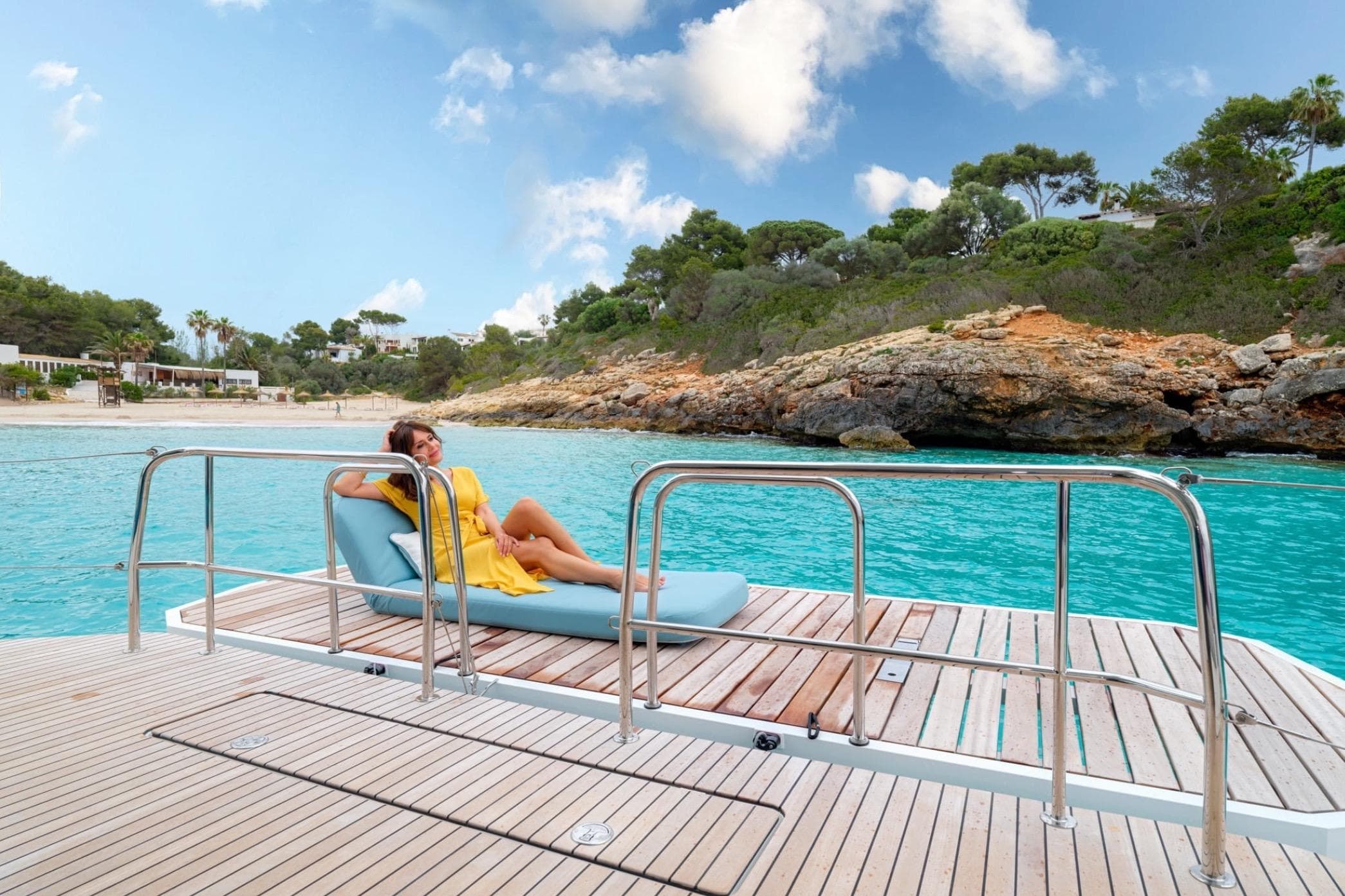 Woman relaxing on Lagoon 55 yacht deck, 2026 model, near scenic coastline.