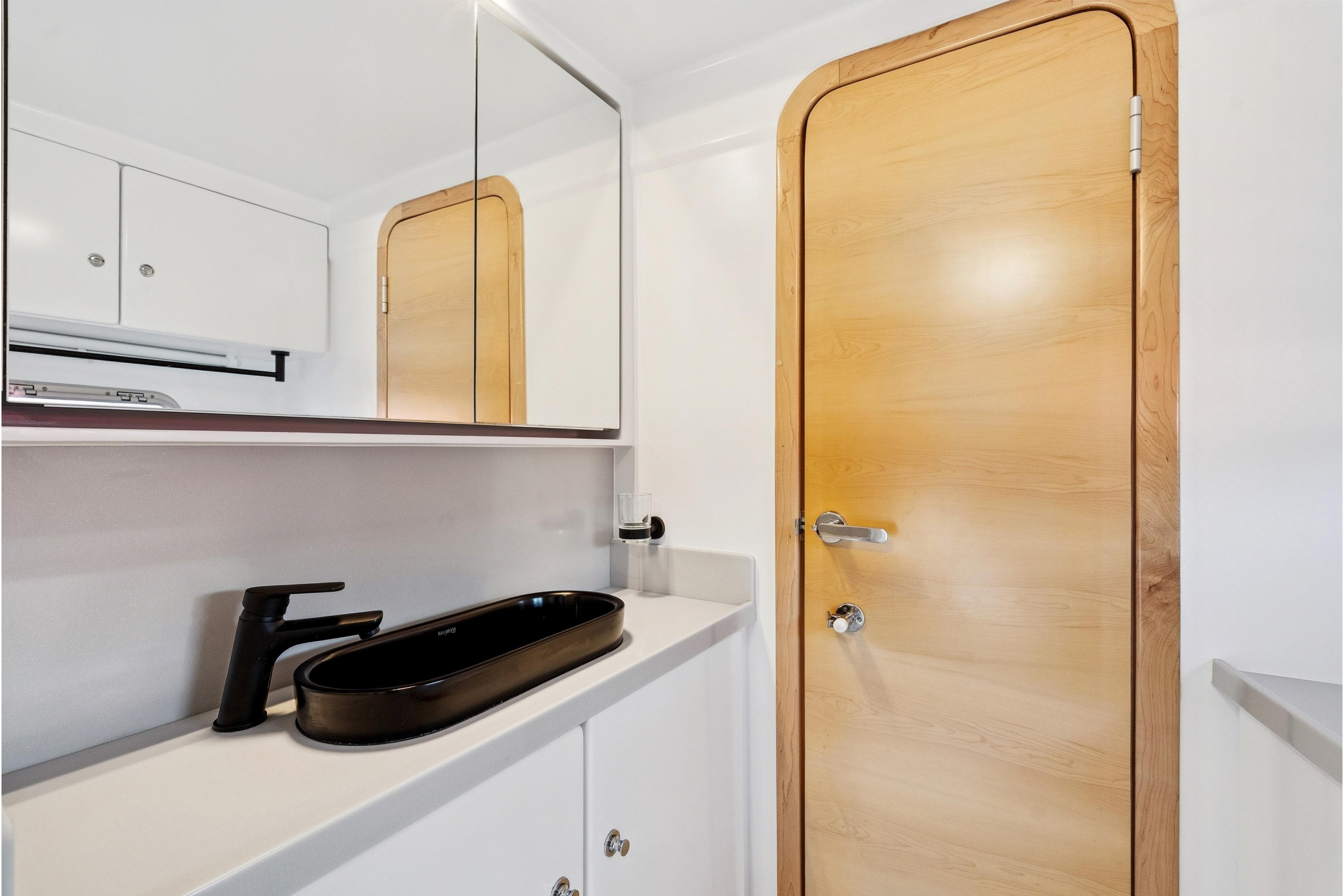 Modern bathroom in 2024 St Francis 460 yacht with sleek black sink and wooden door.