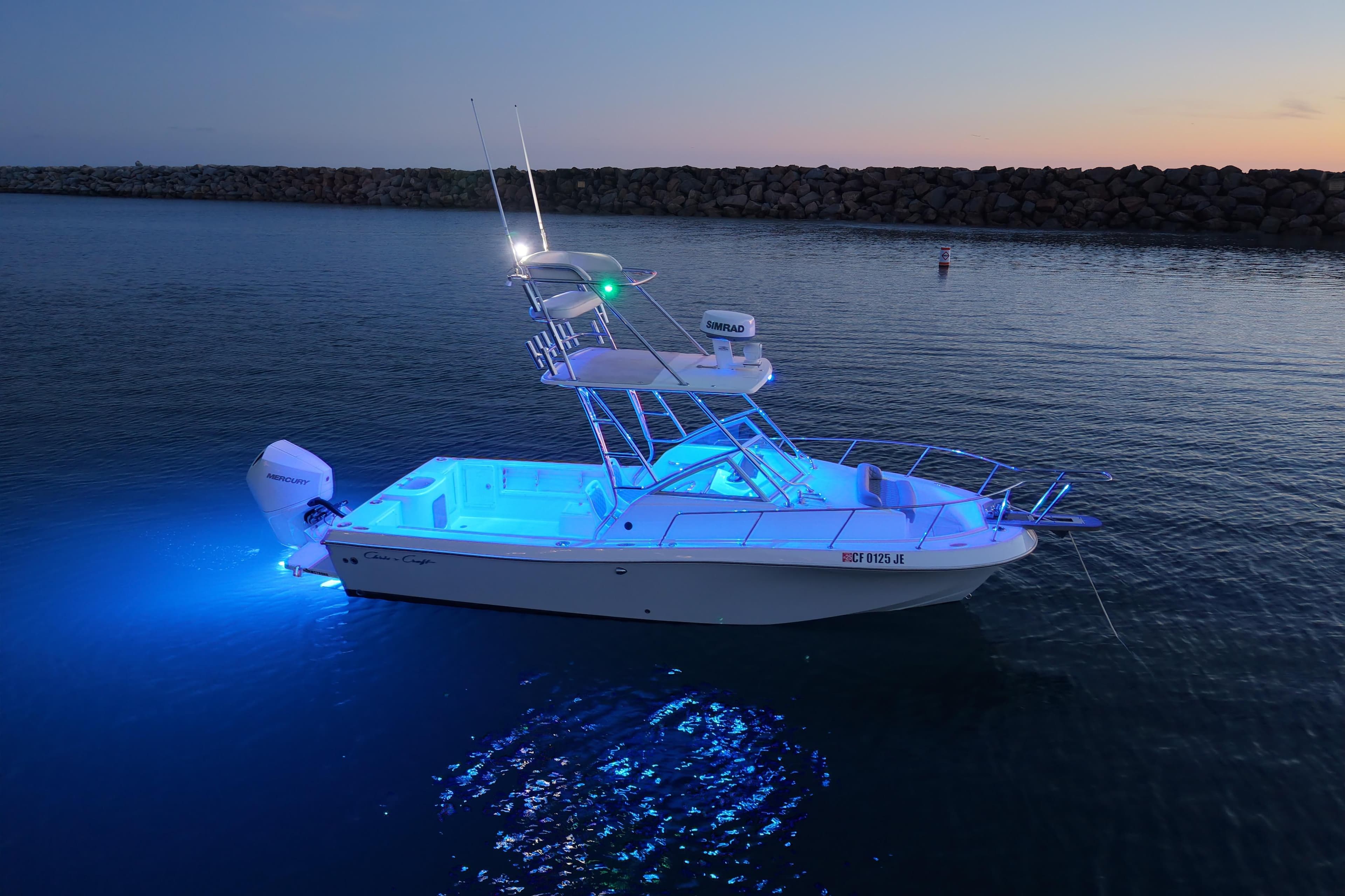 1985 Chris-Craft 21 Scorpion Cuddy boat illuminated on calm water at dusk.
