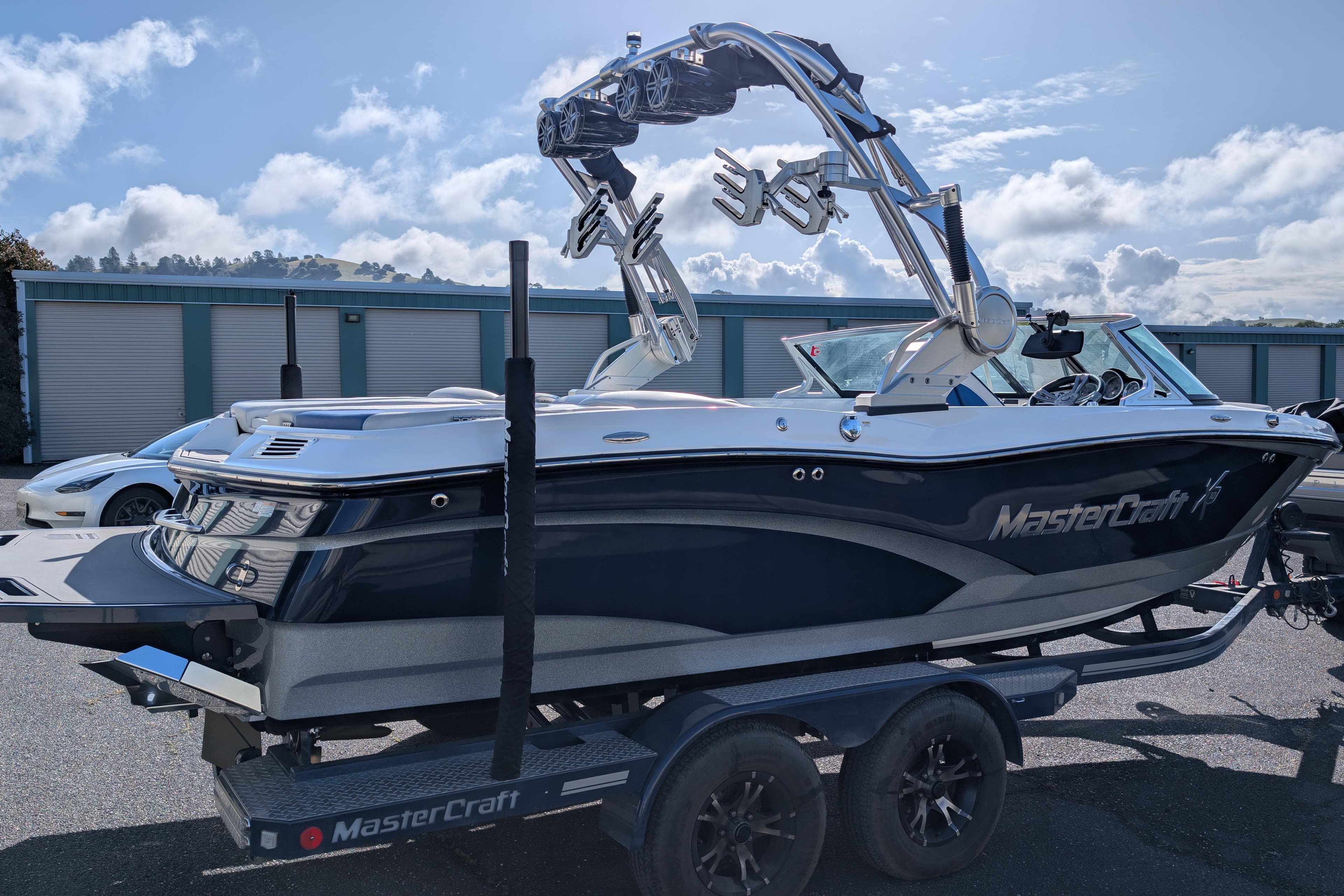 2016 MasterCraft X10 boat on trailer, sleek design, blue and white color, sunny day background.