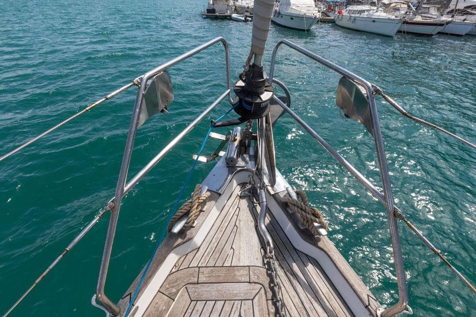 Bow of 1997 Hallberg-Rassy 42 sailboat docked in clear blue water.