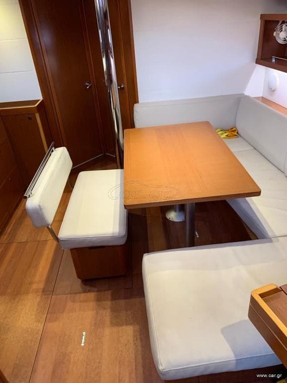 Interior of 2016 Beneteau Oceanis 45 yacht with wooden dining table and cushioned seating.
